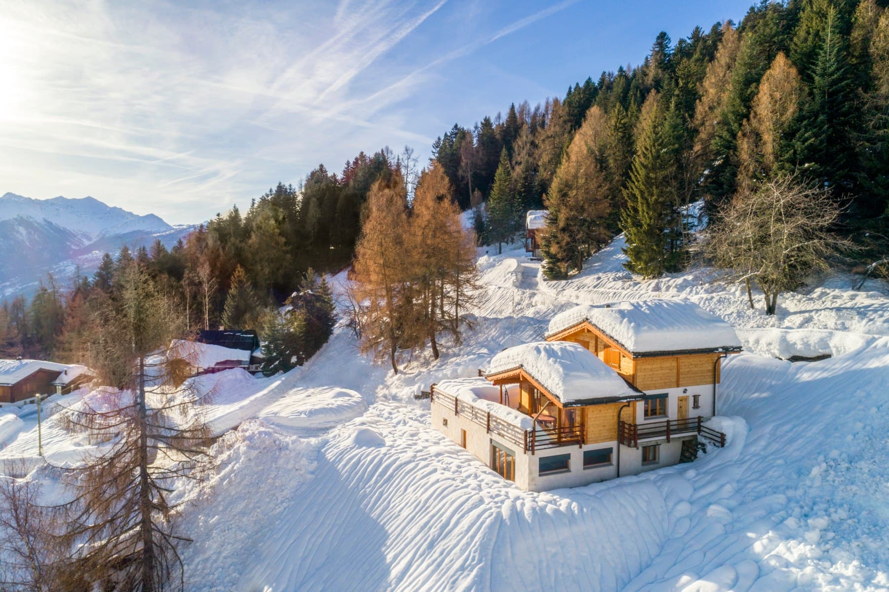 Vue aérienne d’un chalet enneigé, entouré de mélèzes et de sapins