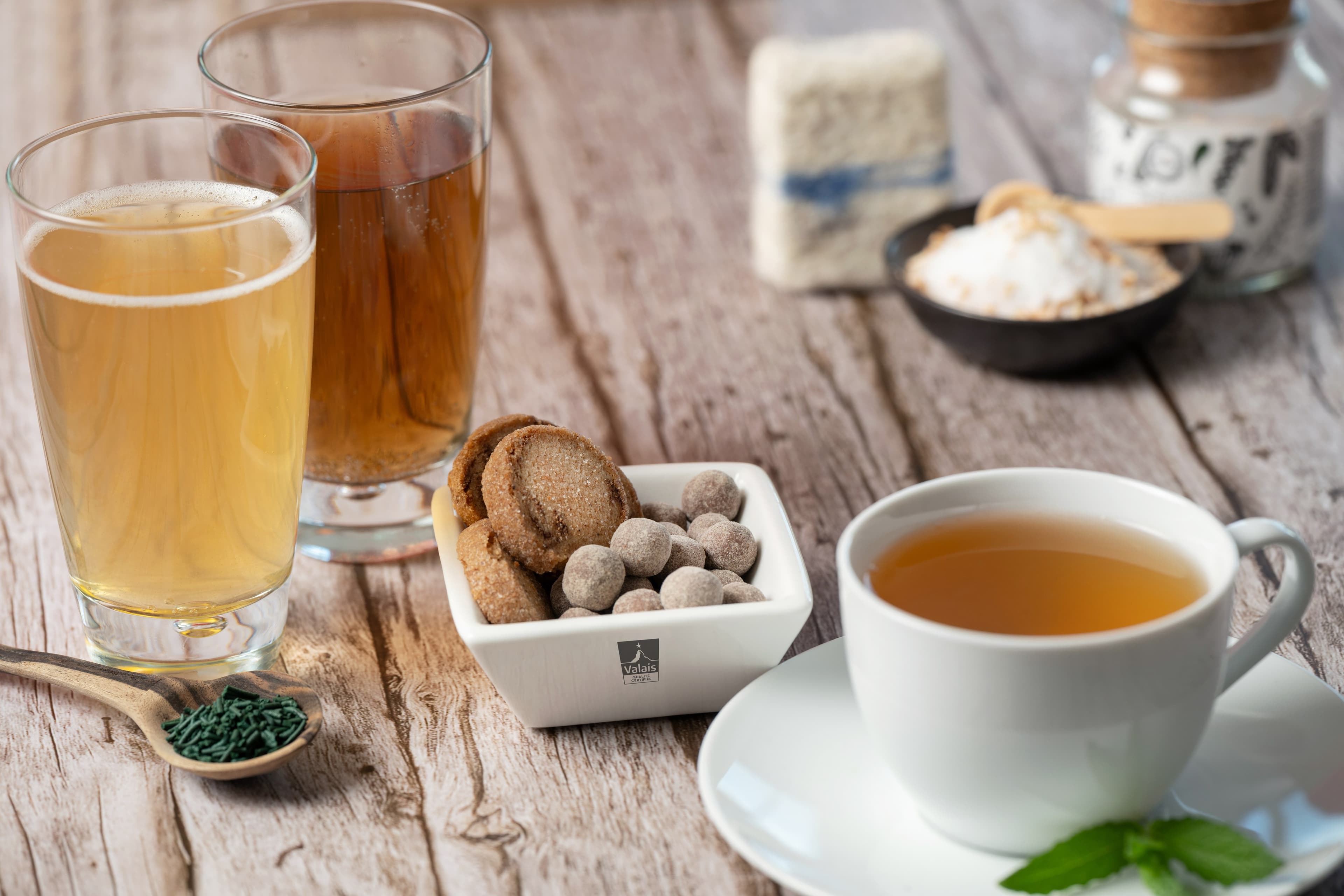 Thé, jus de fruits et biscuits de producteurs valaisans mis en scène sur une table en bois