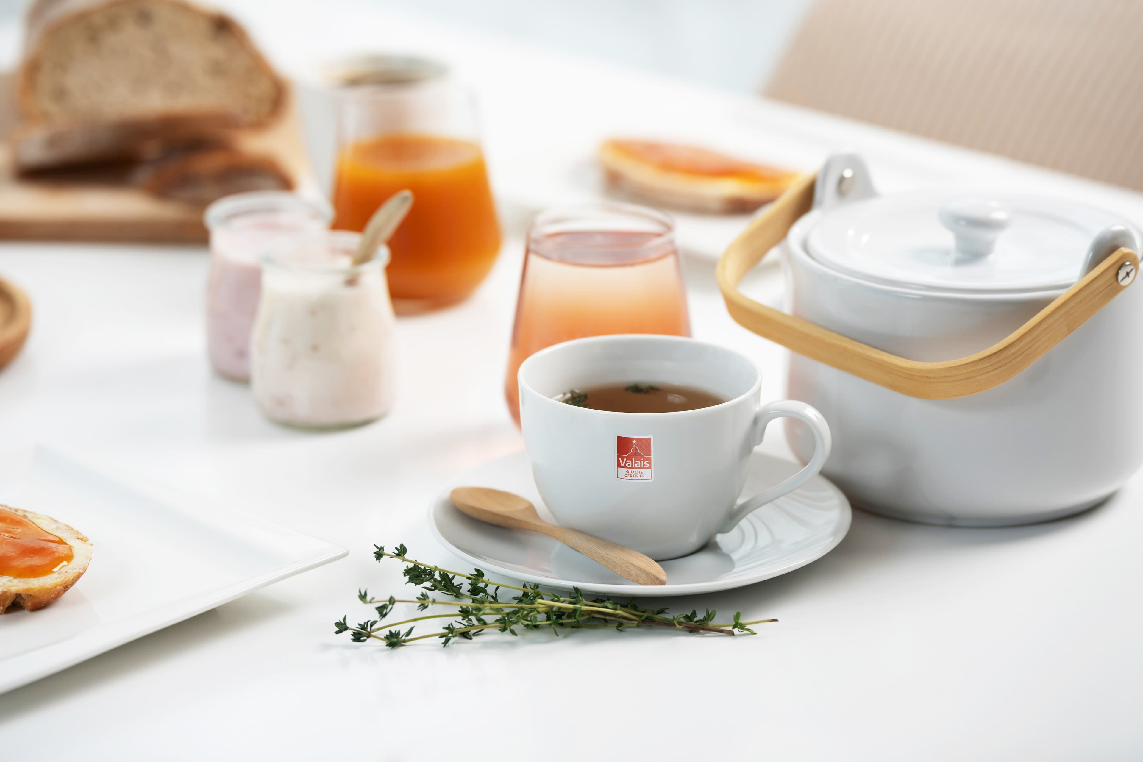 Petit-déjeuner avec confiture, yogourt et théière sur une table claire