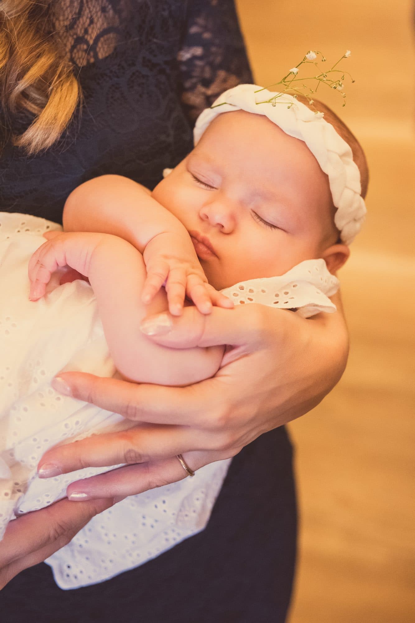 Un bébé endormi, une couronne dorée sur la tête, dans les bras de sa maman