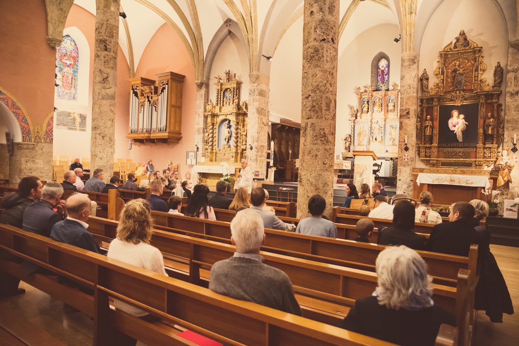 L’assemblée assise dans les bancs d’une église voûtée, face aux autels dorés