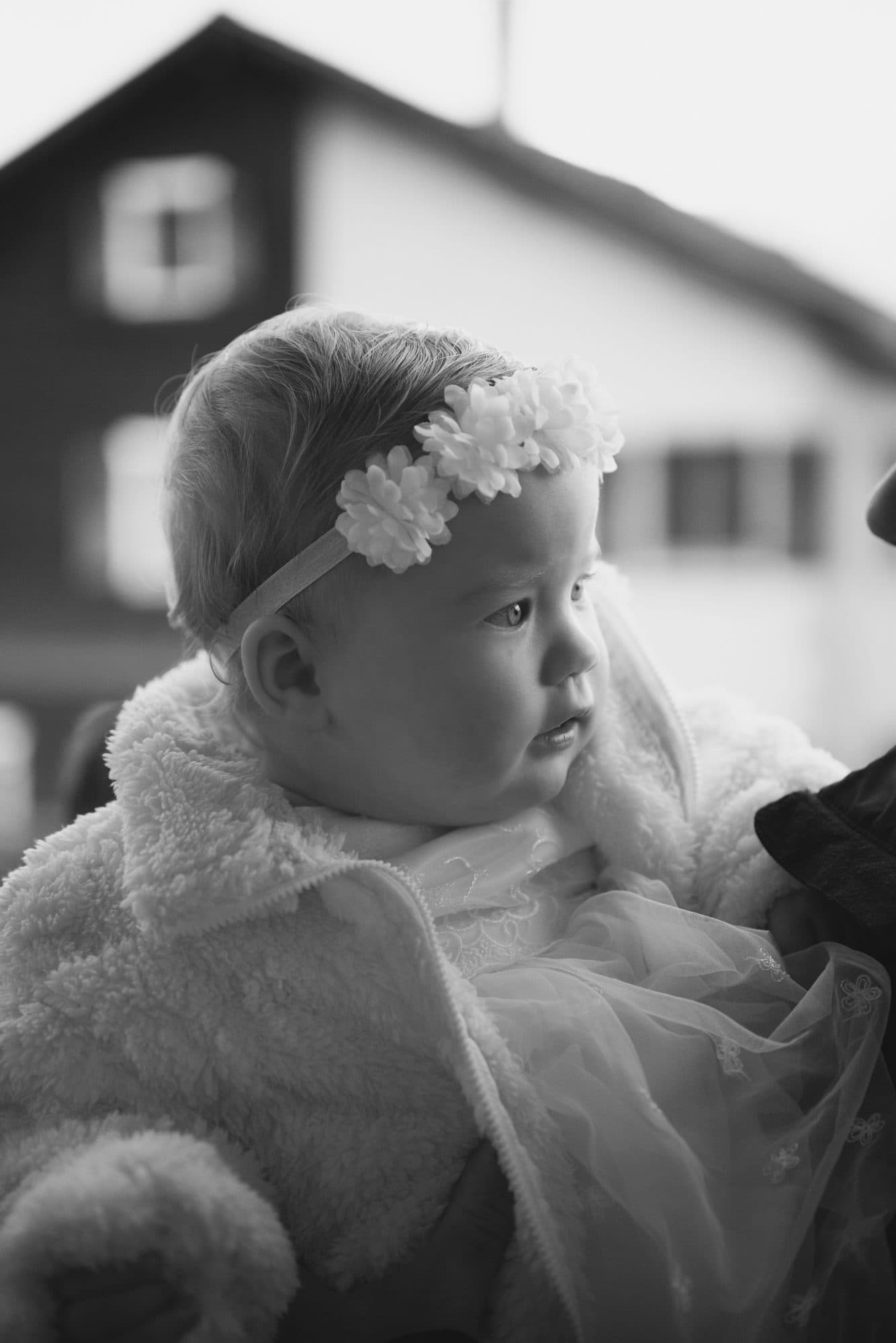 Une petite fille au bandeau fleuri regarde au loin, en noir et blanc