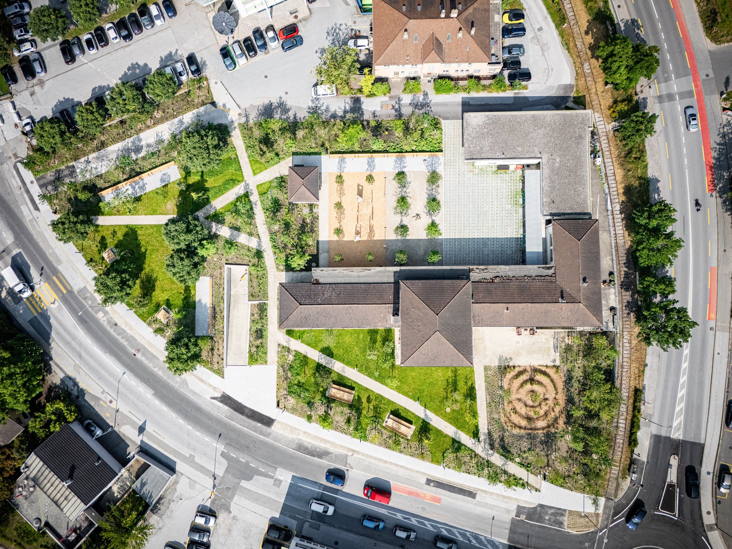 Vue au drone à la verticale de L’Archipel, ses toits, ses jardins et ses chemins entre deux rues, aménagement urbain à Sion