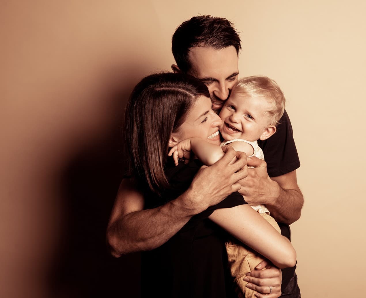 Les mêmes parents rient avec leur bébé dans les bras