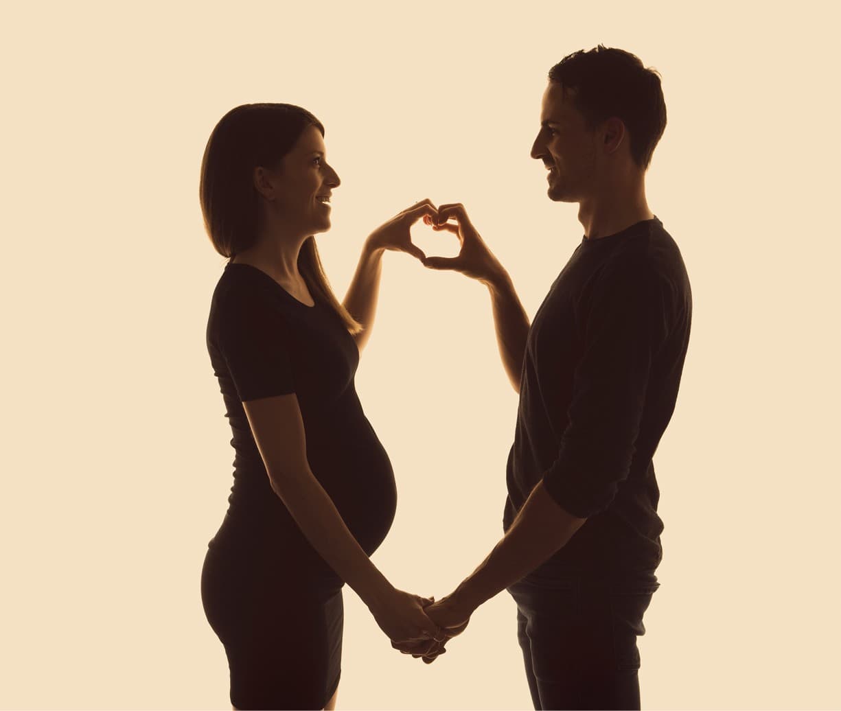 Un couple en silhouette forme un cœur avec ses mains