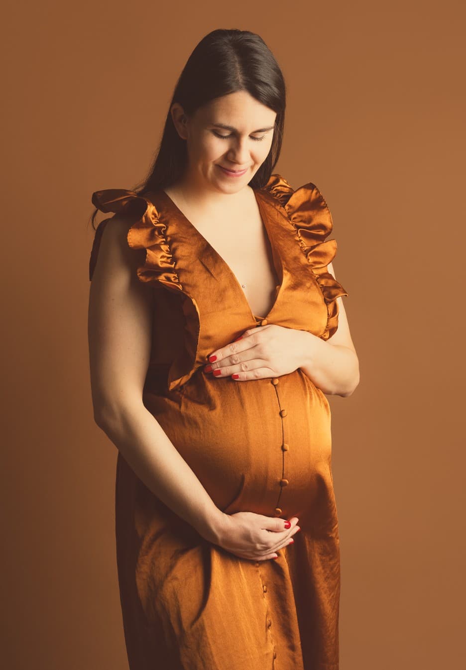 Future maman en robe satinée rouille à volants, fond caramel