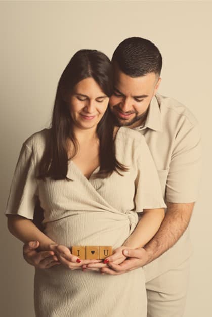 Futurs parents en tenues beiges, des cubes en bois dans les mains devant le ventre