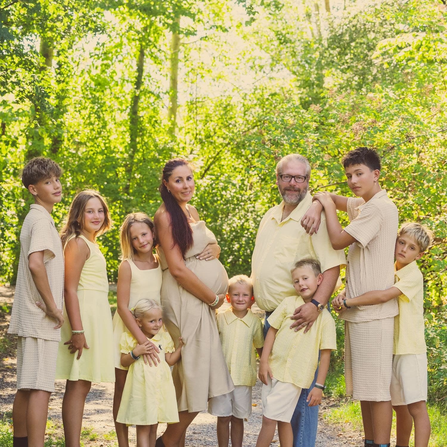 Une future maman entourée de sa grande famille en extérieur, parents, enfants et grands-parents réunis