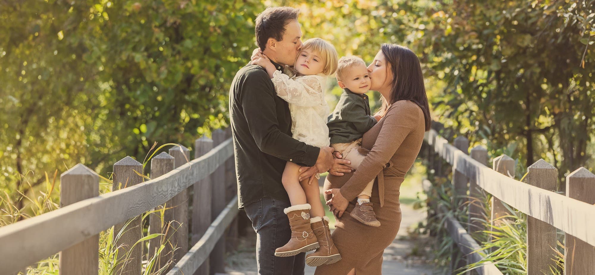 Une famille sur une passerelle en bois en automne, la future maman au centre