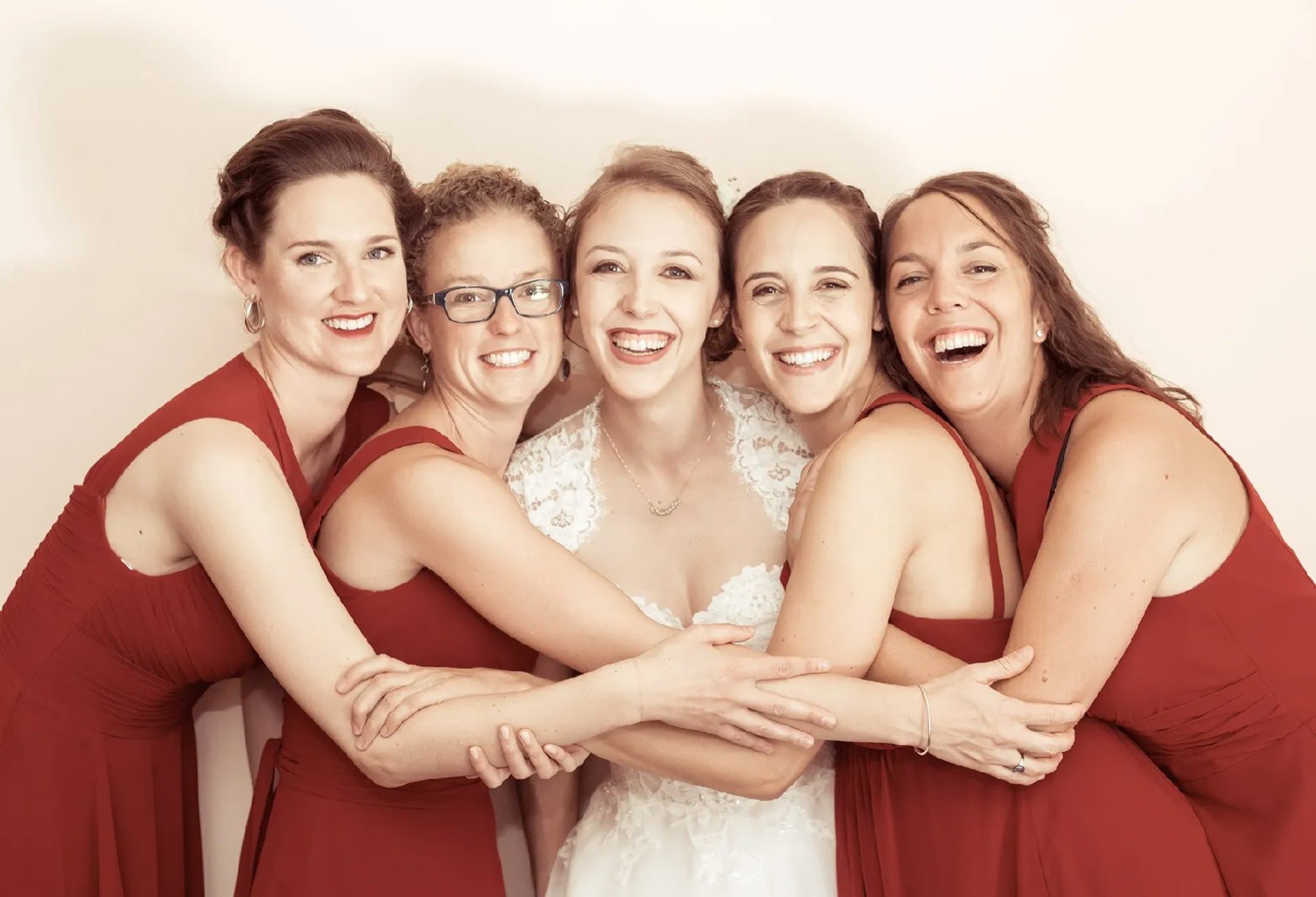 La mariée serrée dans les bras de ses quatre amies en robes rouges