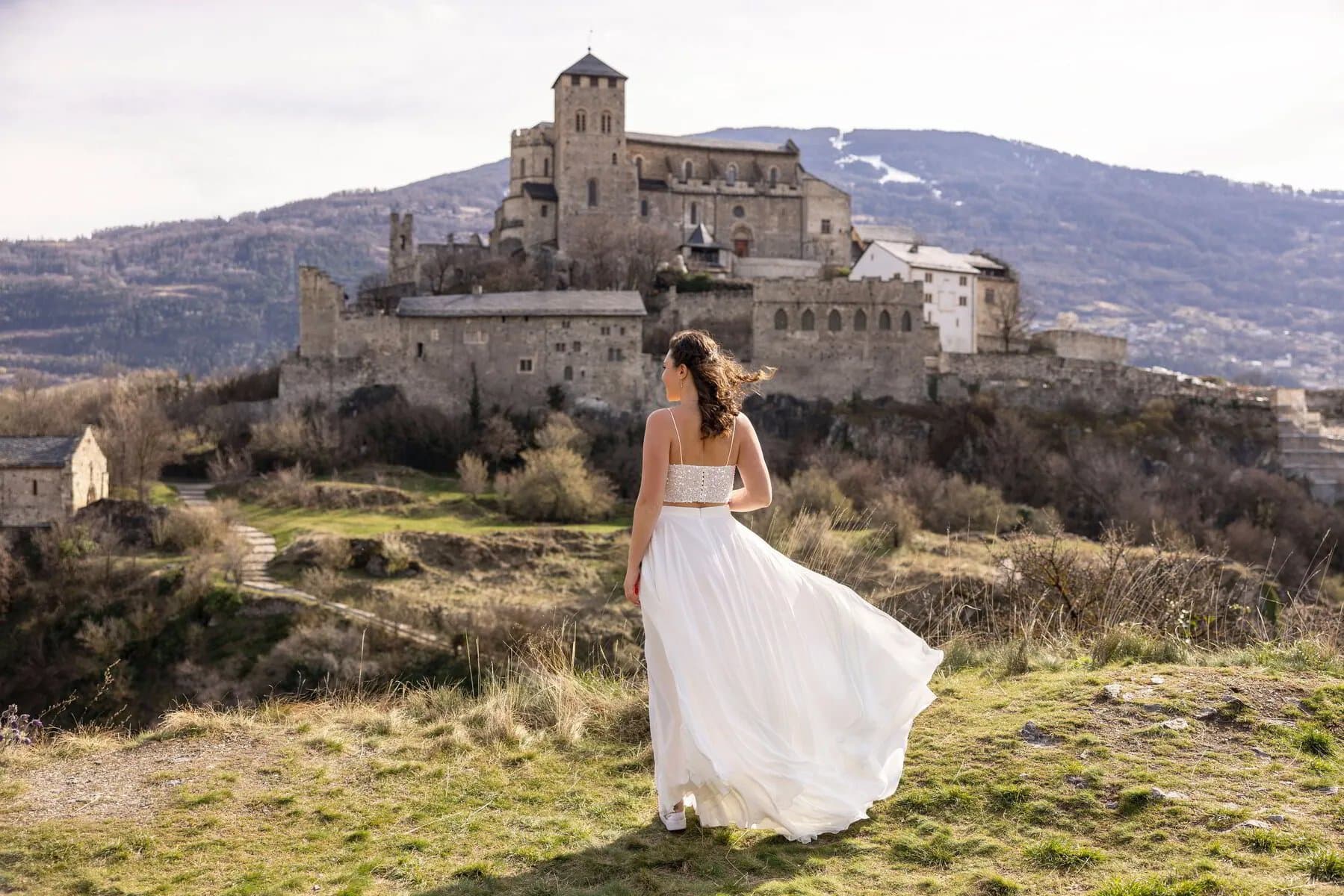 La mariée, robe au vent, face à la basilique de Valère à Sion