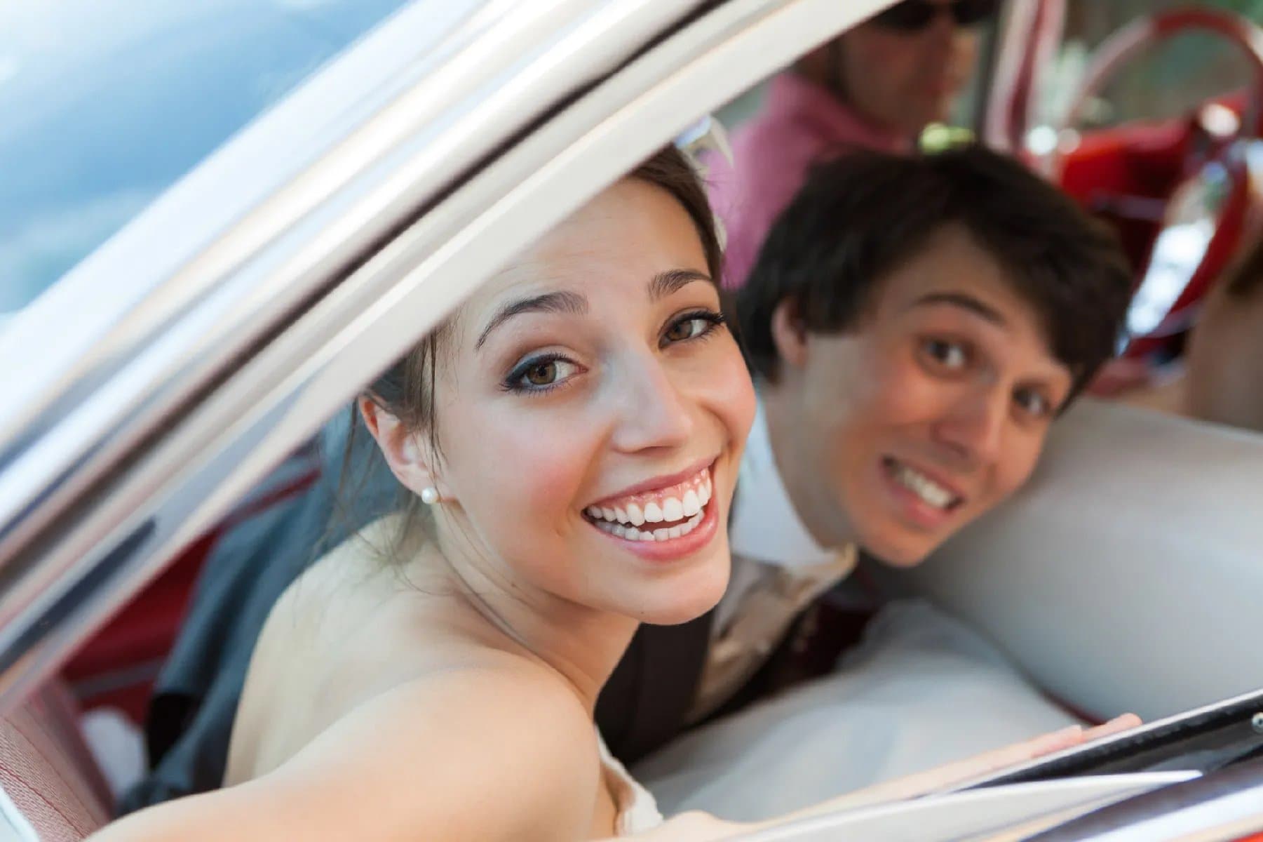 Les mariés souriants à la fenêtre de leur voiture