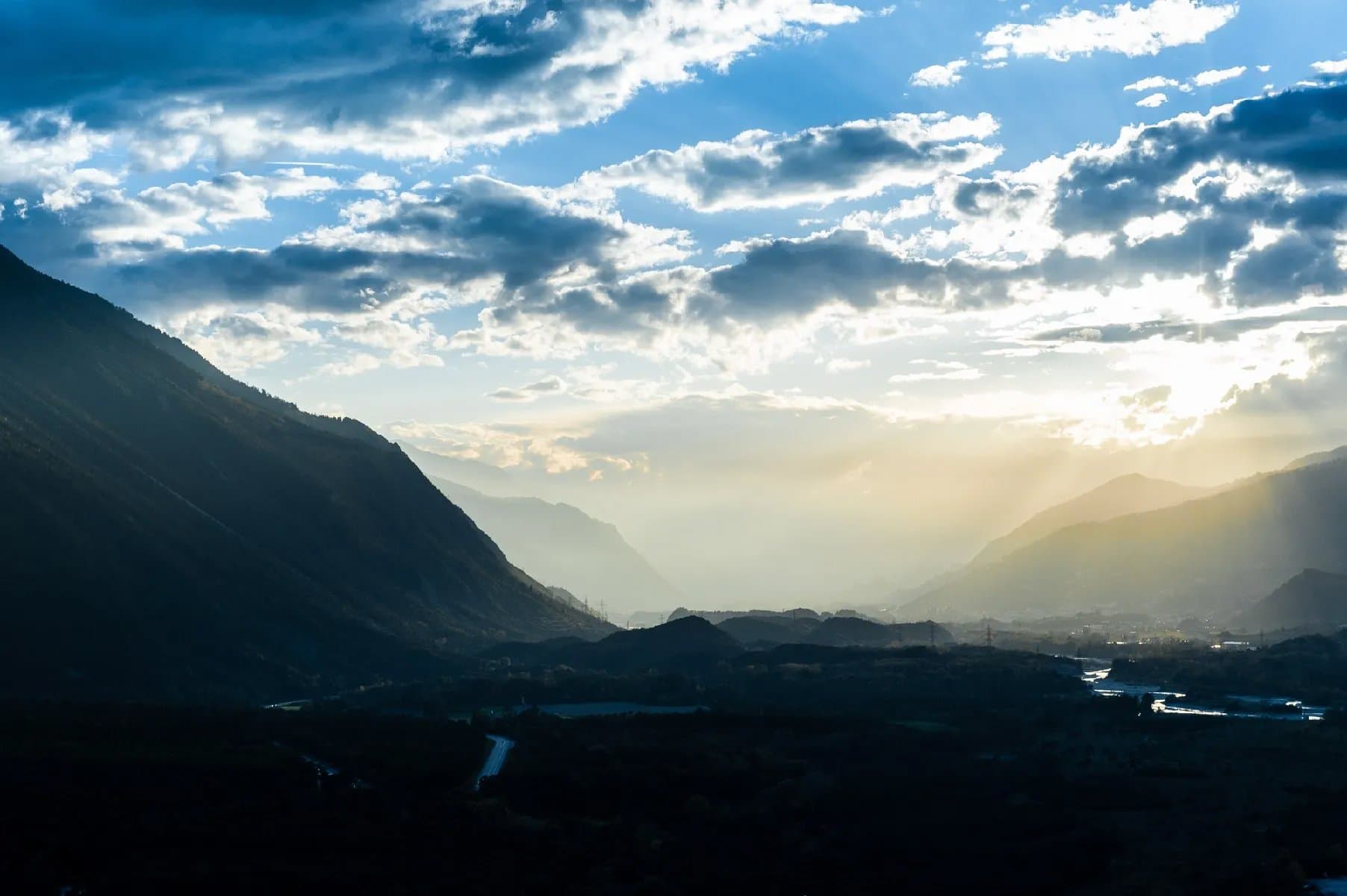 Une vallée de montagne sous un ciel chargé, en fin de journée