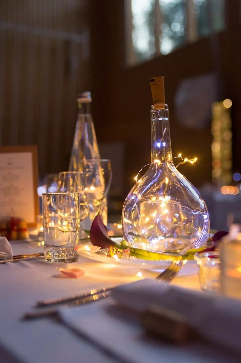 Table de fête décorée d’une bouteille garnie d’une guirlande lumineuse