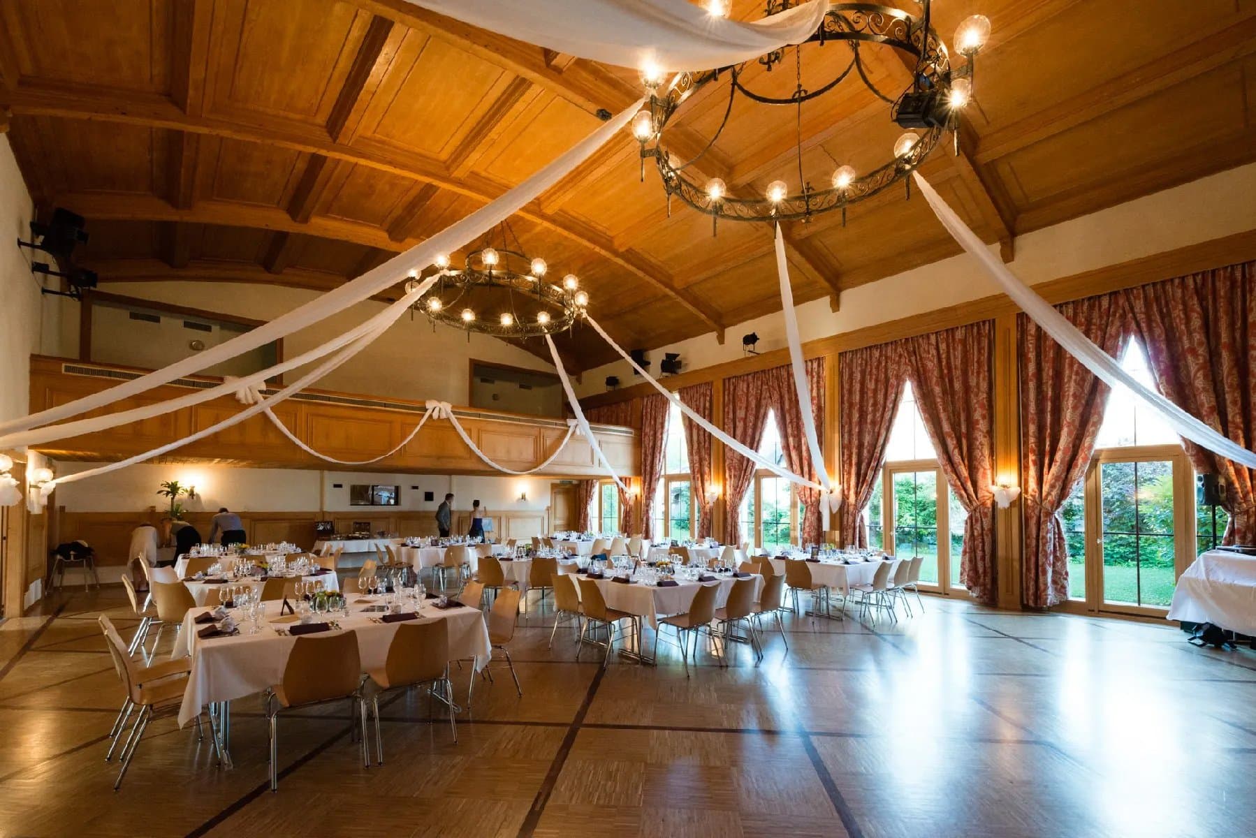 Salle de réception décorée de voilages blancs et de lustres, tables dressées