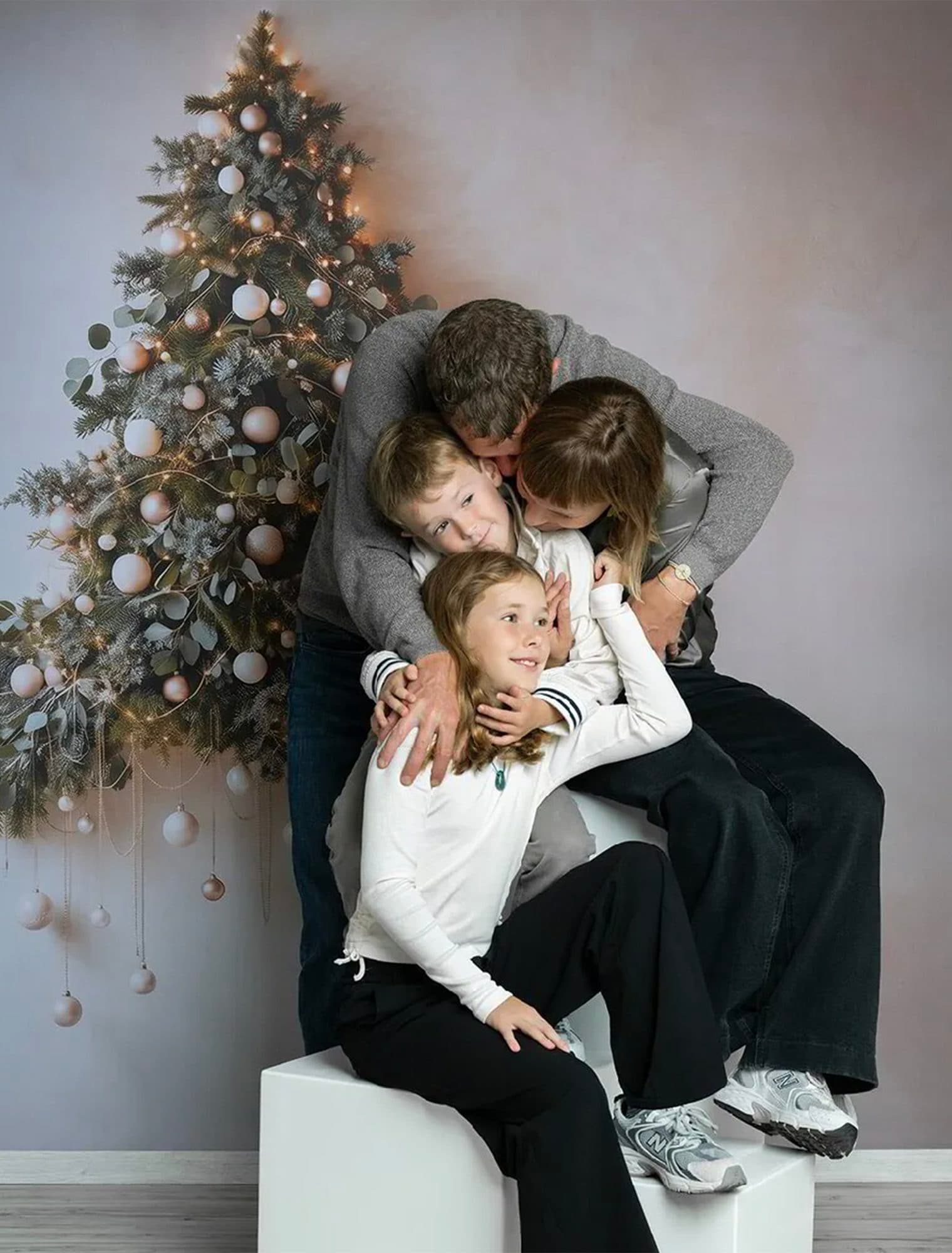 Décor Le Grand Sapin : une famille enlacée sur un cube blanc, devant le sapin de Noël