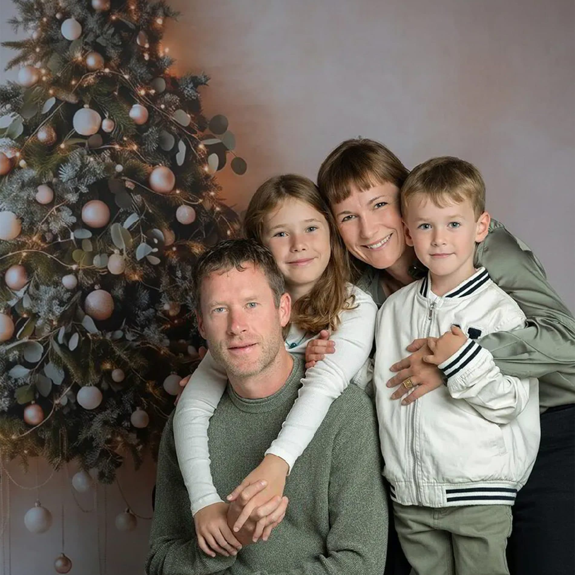 Une famille serrée devant un sapin de Noël aux boules claires