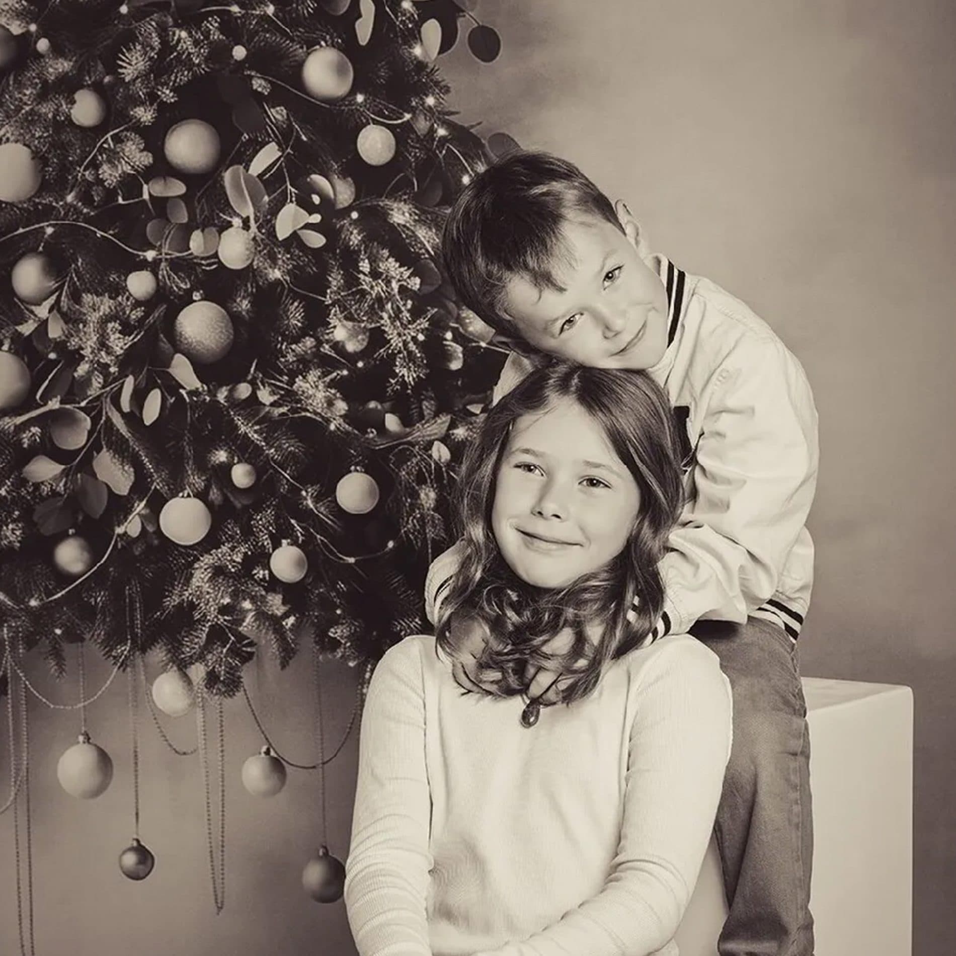 Un frère et sa sœur devant un sapin de Noël, en tons sépia