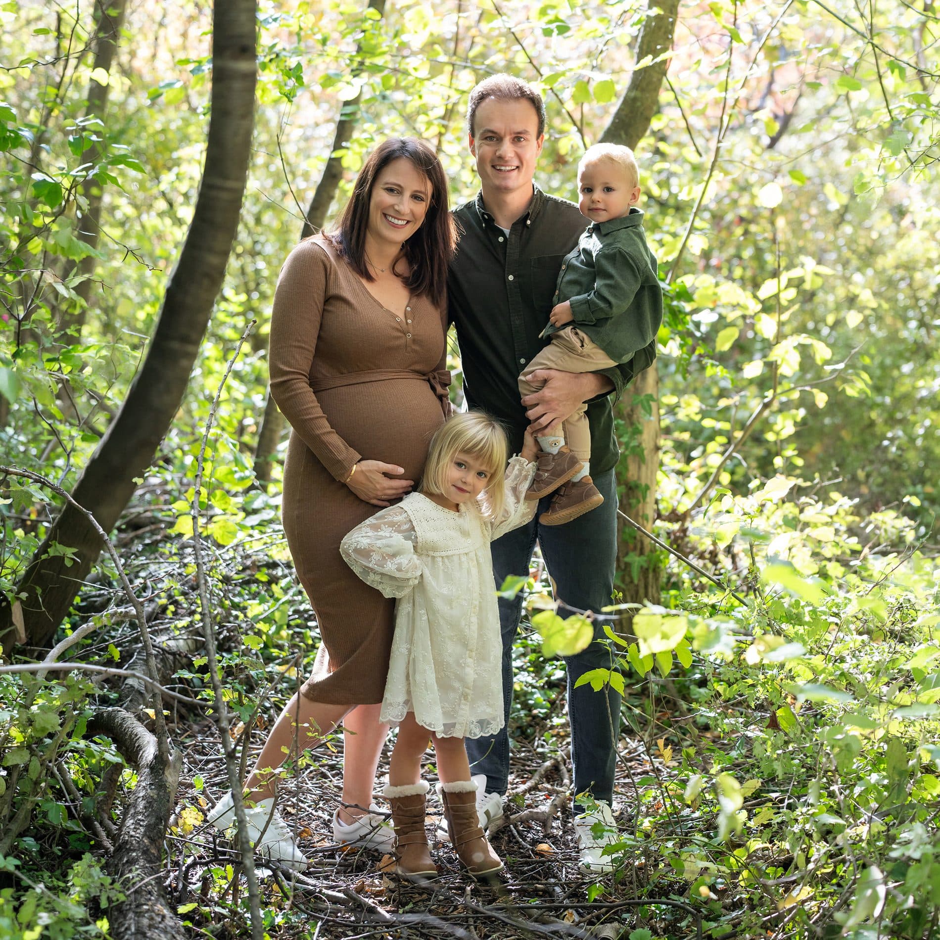 Une famille debout en forêt, le papa porte son petit garçon