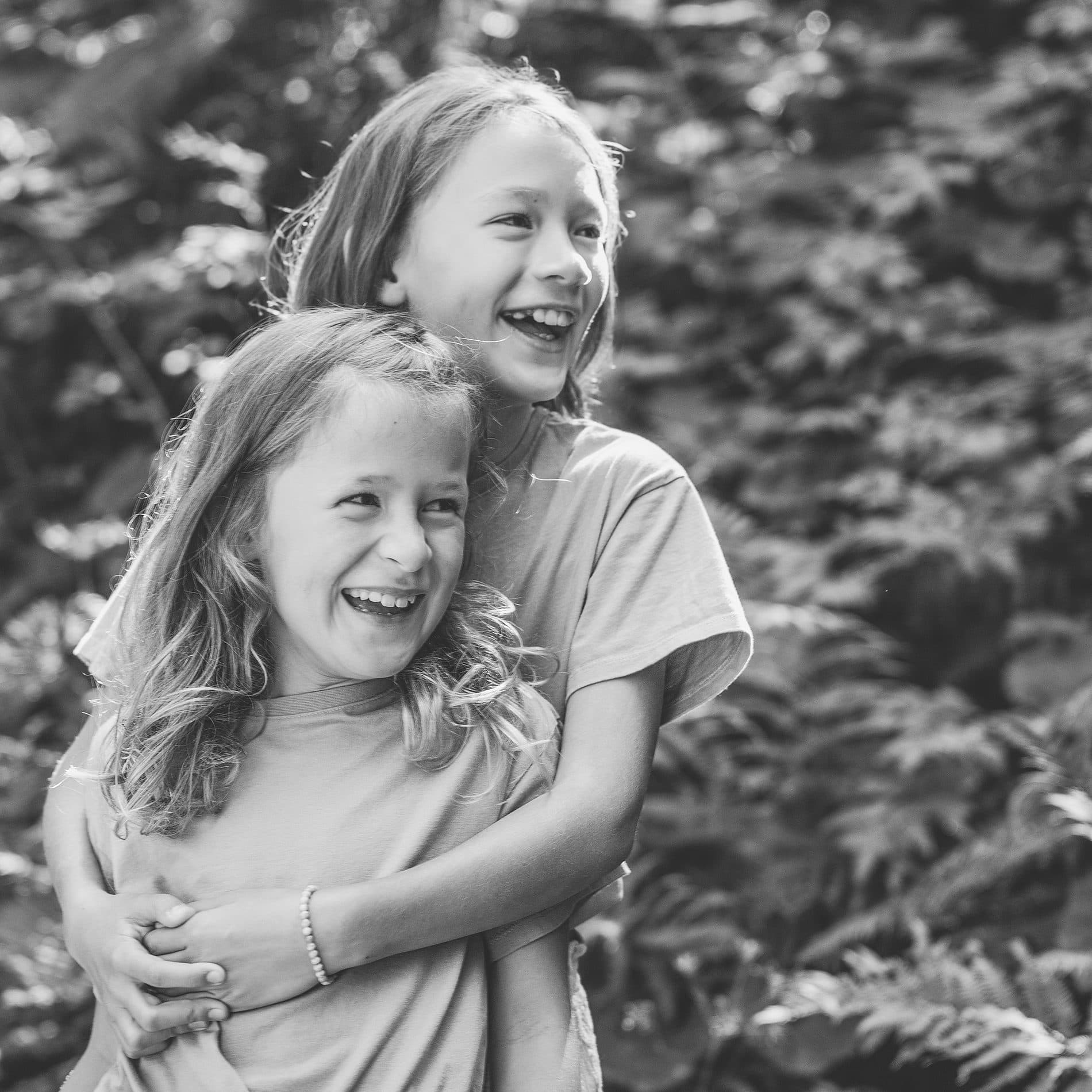 Deux sœurs rieuses enlacées, en noir et blanc
