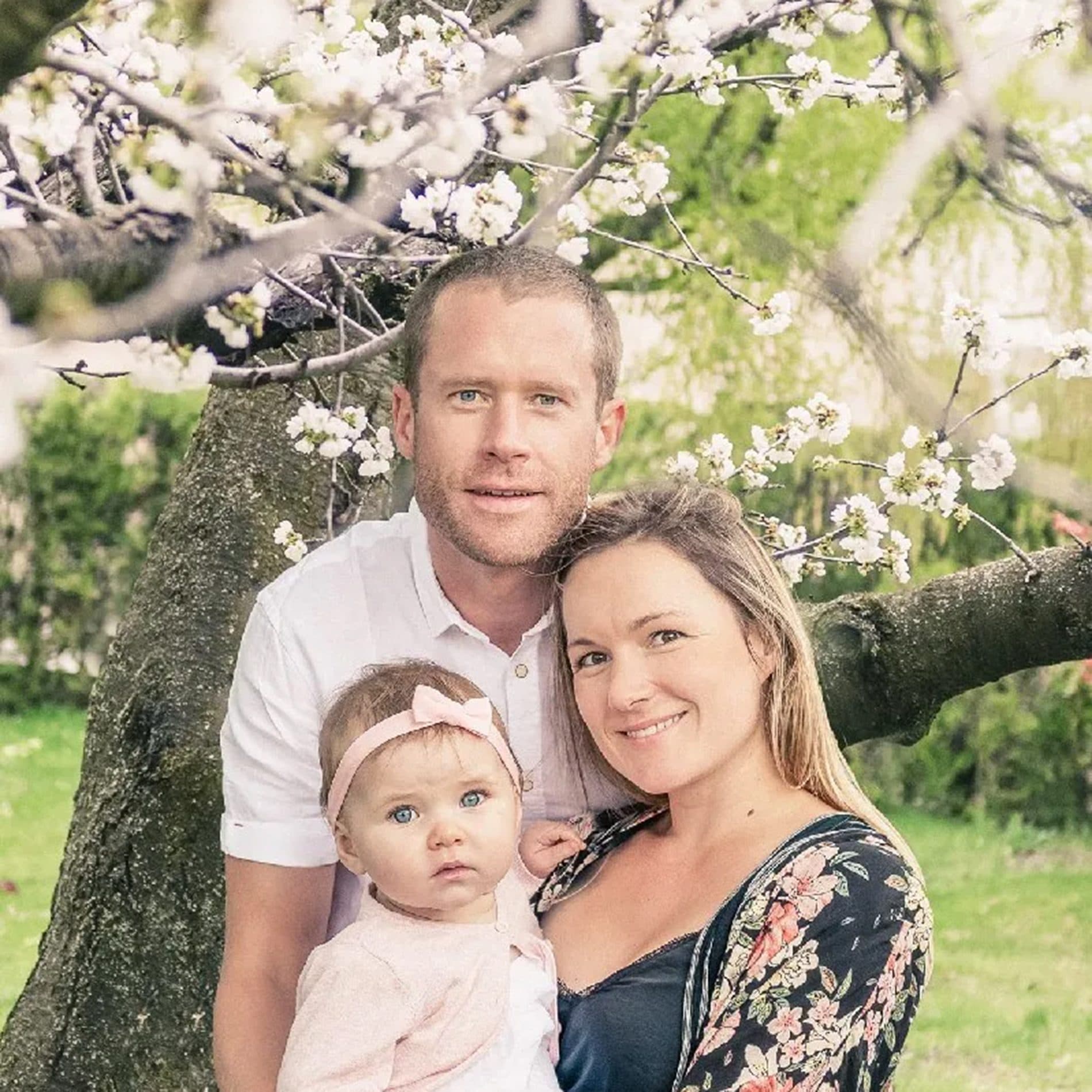Des parents et leur bébé sous un arbre en fleurs