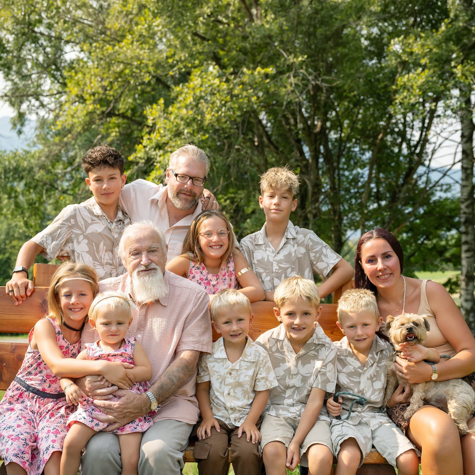 Une grande famille de trois générations réunie sur un banc, dans un jardin