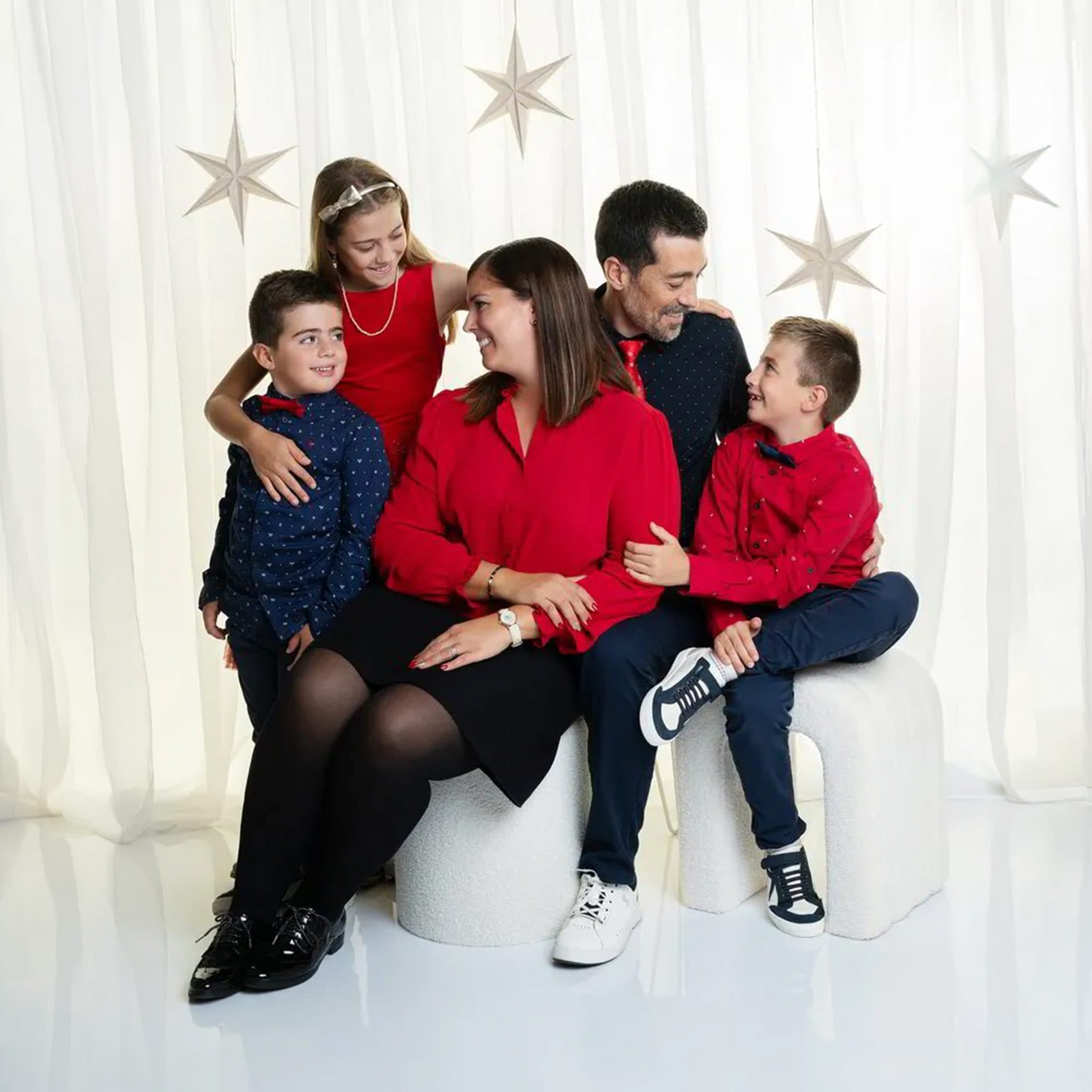 Une famille habillée de rouge et de noir sur des cubes blancs, devant des étoiles