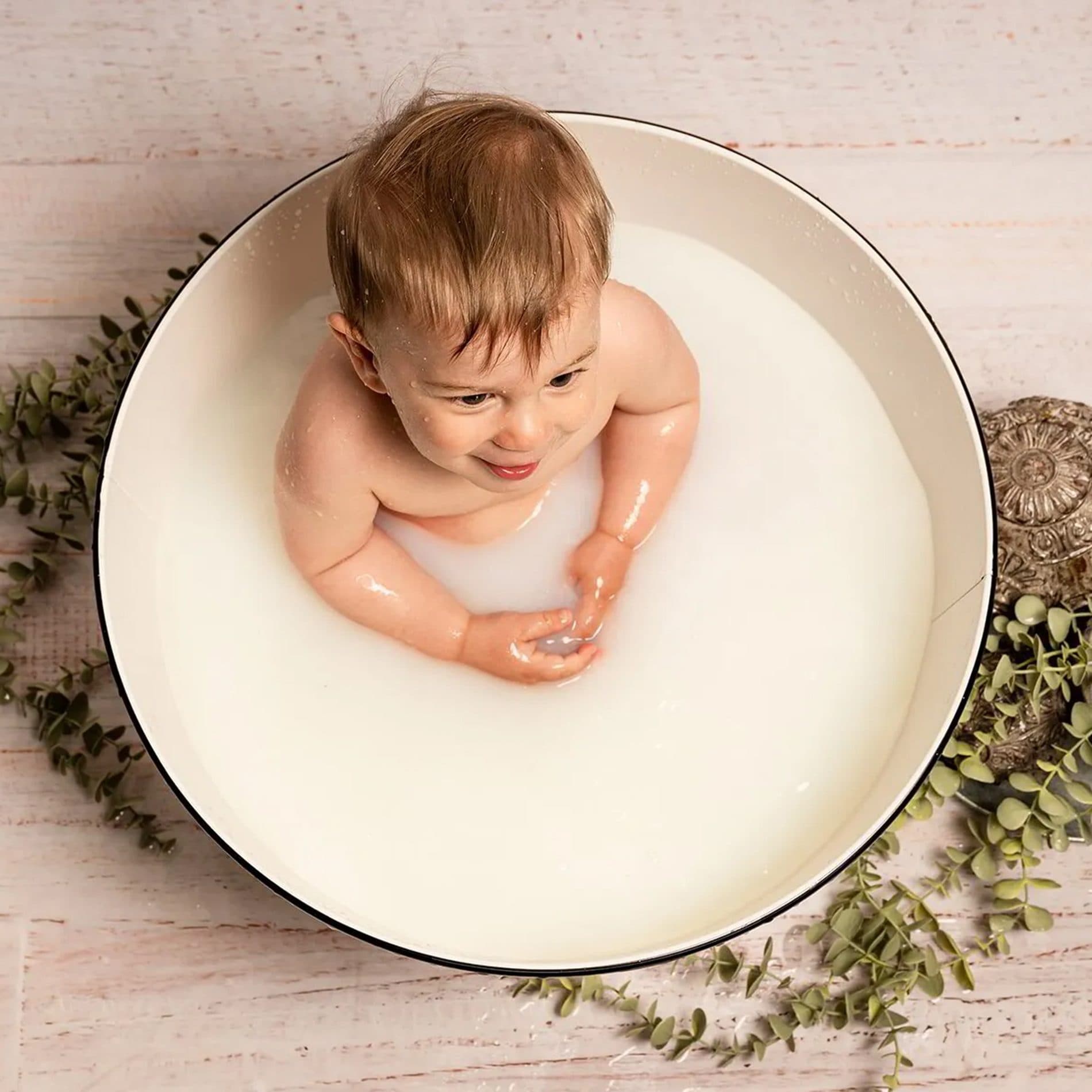 Un bébé joue dans l’eau d’une bassine, vu de dessus
