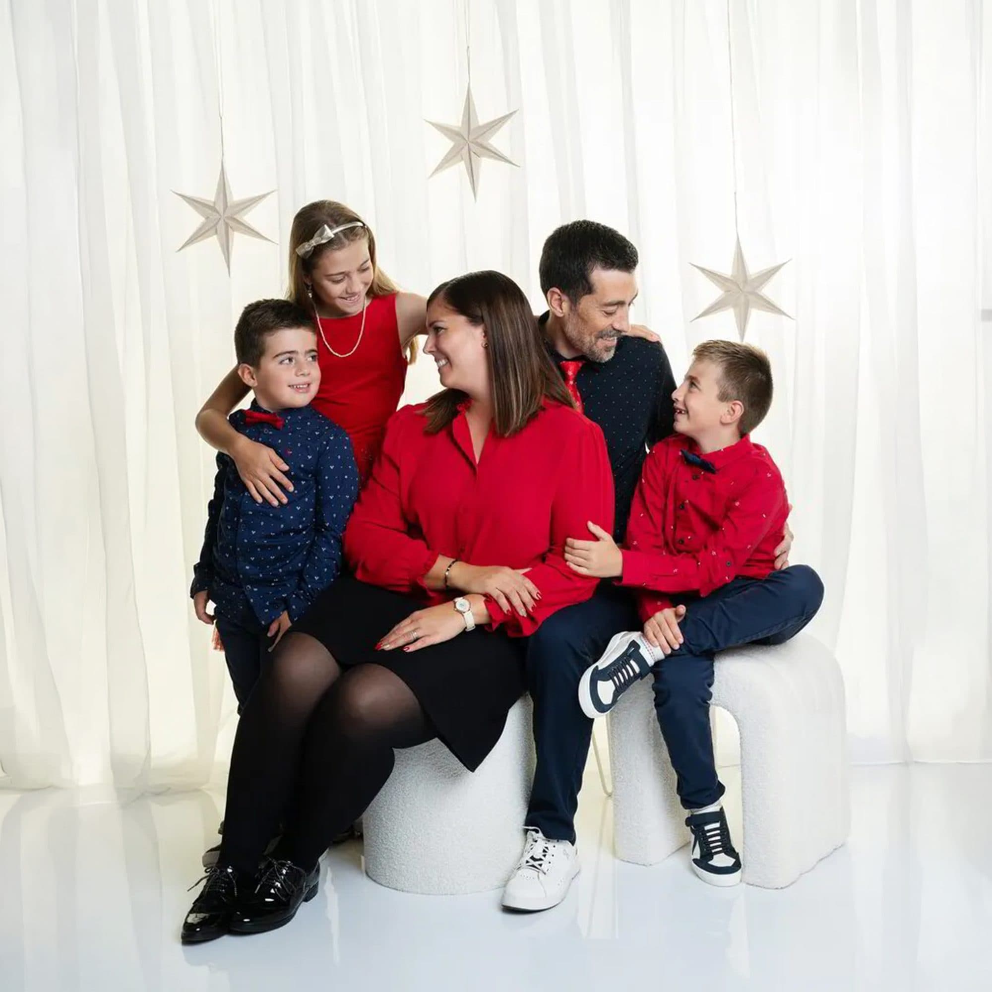 Une famille habillée de rouge, de noir et de blanc, assise devant un rideau clair orné d’étoiles