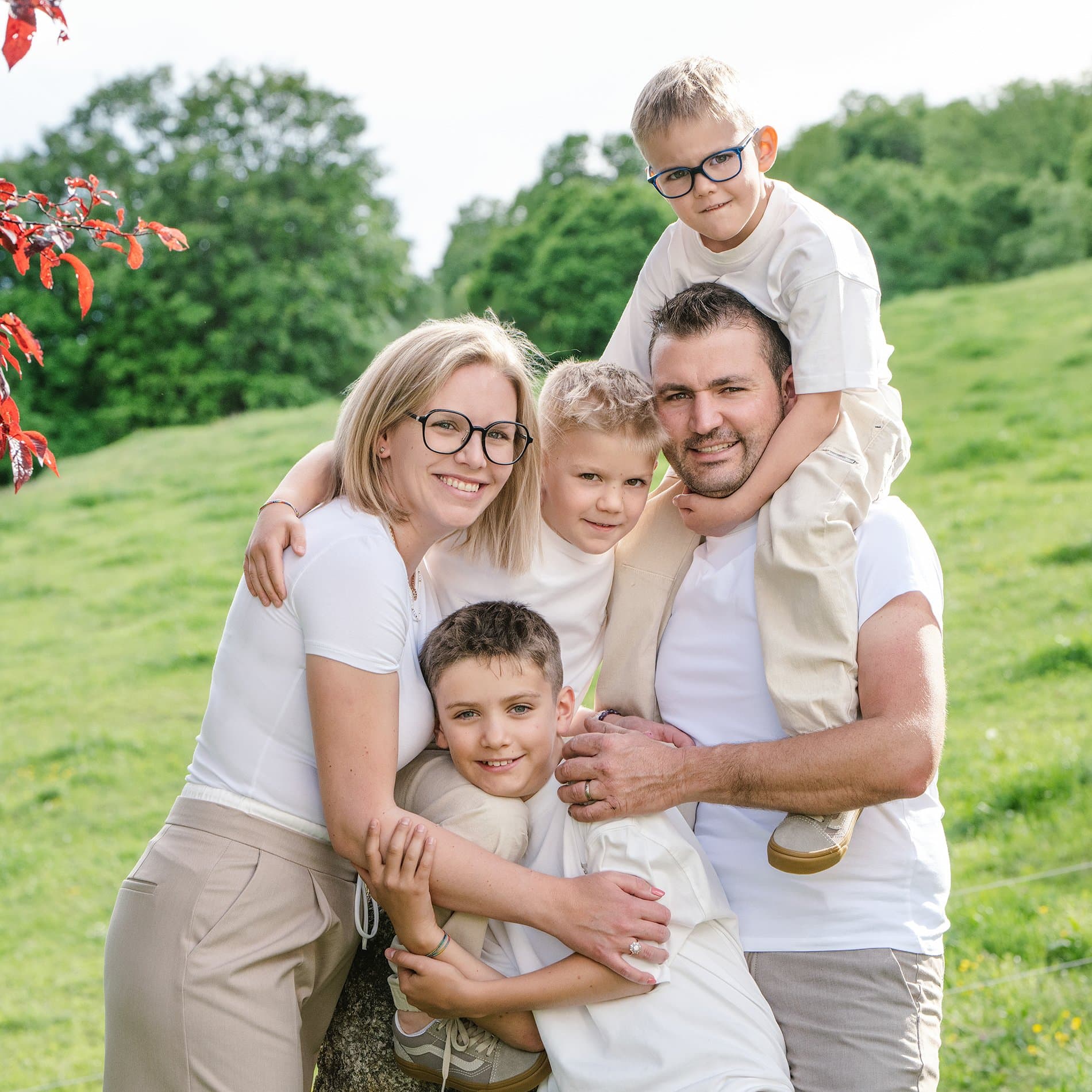Des parents et leurs trois garçons serrés dans une prairie, l’un d’eux sur les épaules du papa