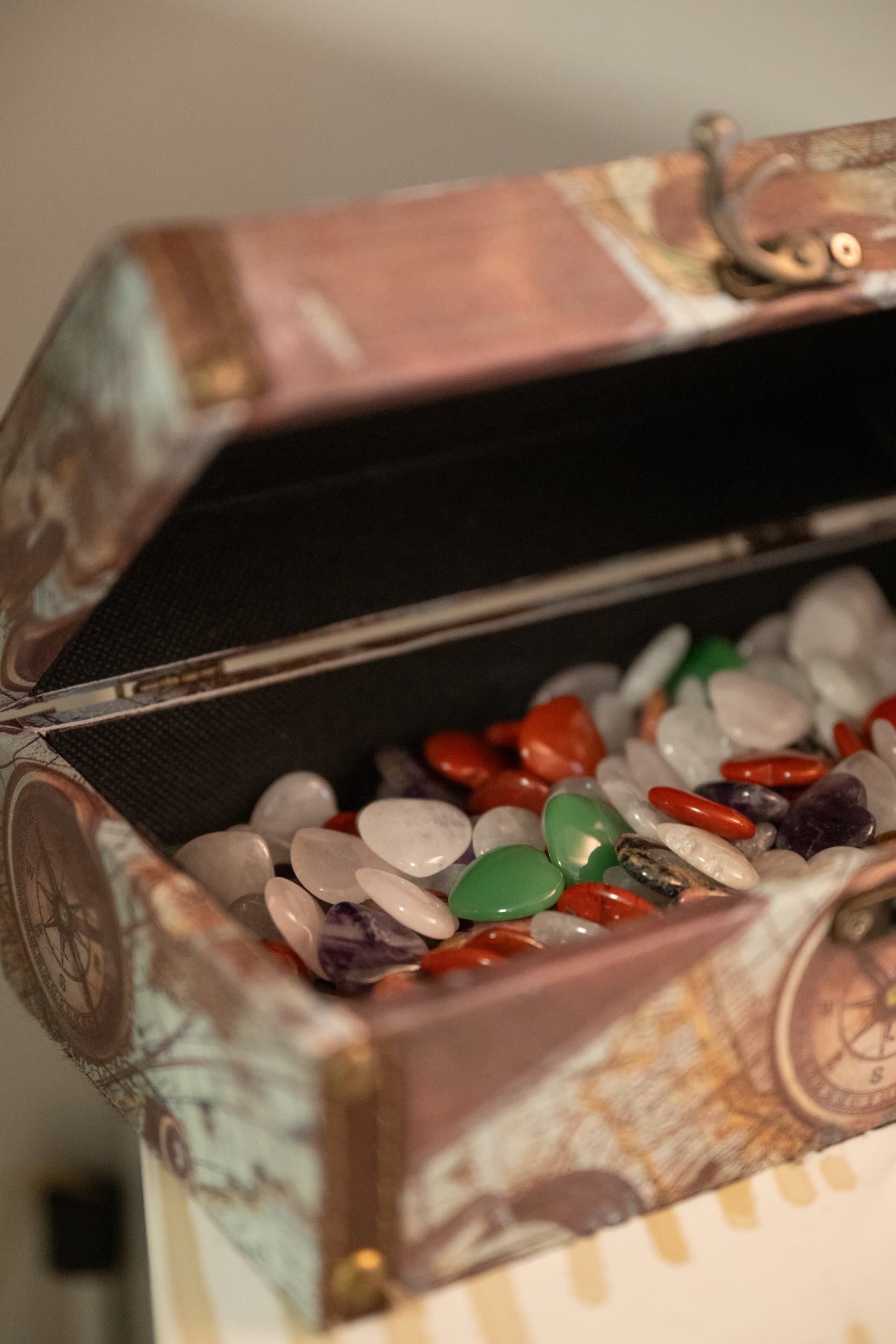 Un coffret ancien ouvert, rempli de pierres polies de couleurs