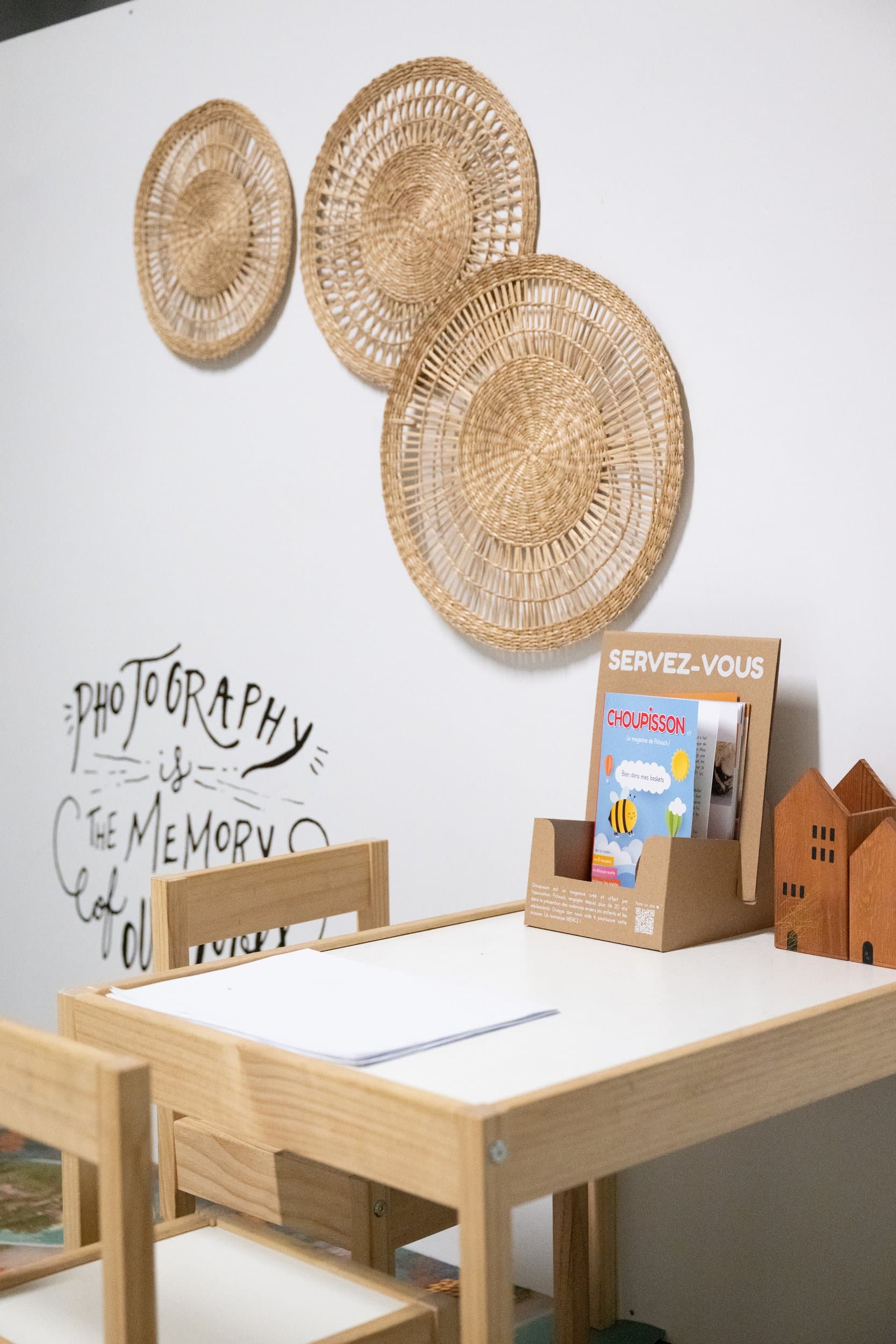 Le coin des enfants à l’accueil : une petite table en bois, deux chaises, des feuilles à dessin et des magazines