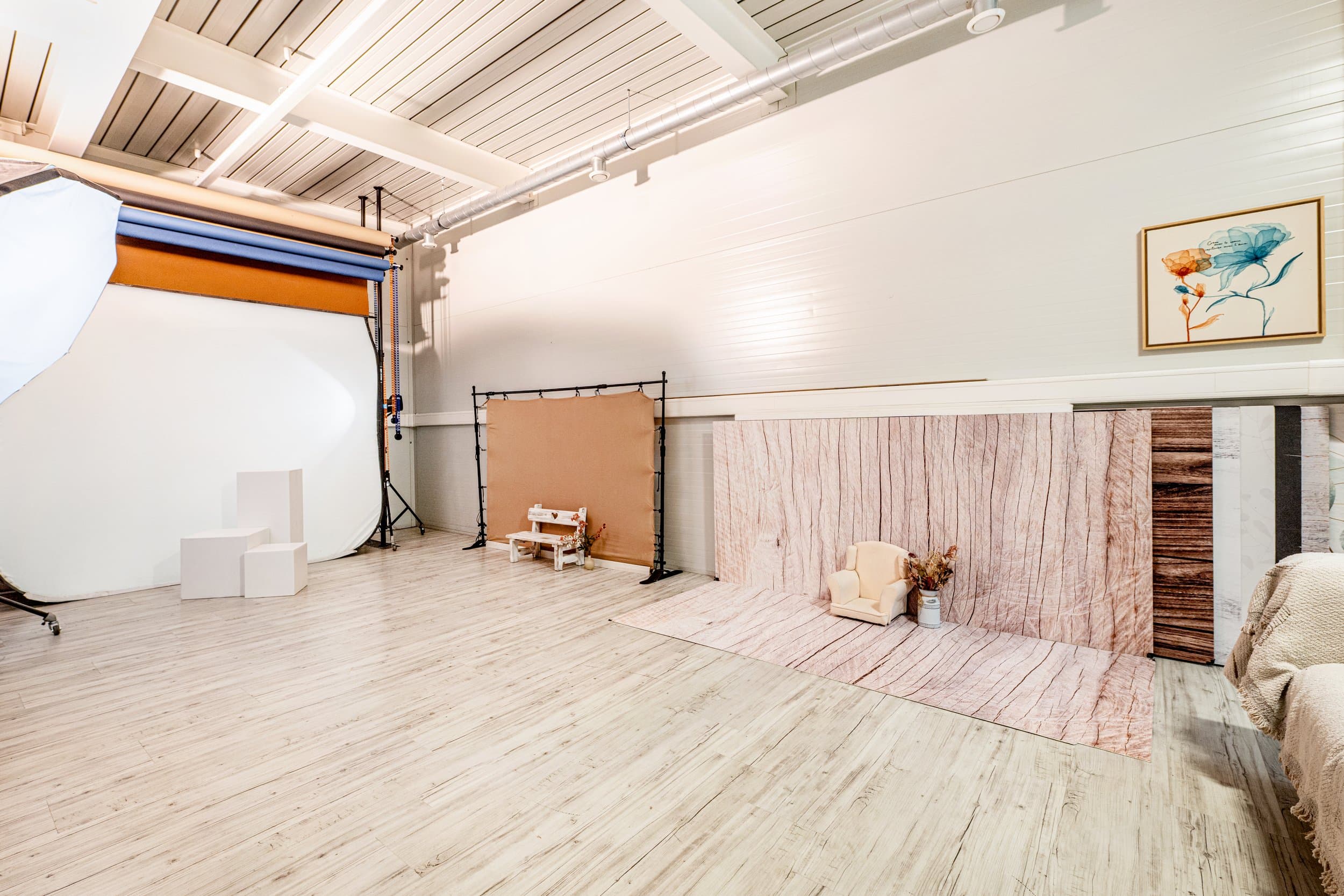 Le côté prise de vue du studio : un grand fond blanc arrondi, des rouleaux de fonds de couleur, des cubes blancs, un fond kraft et un fond imitation bois