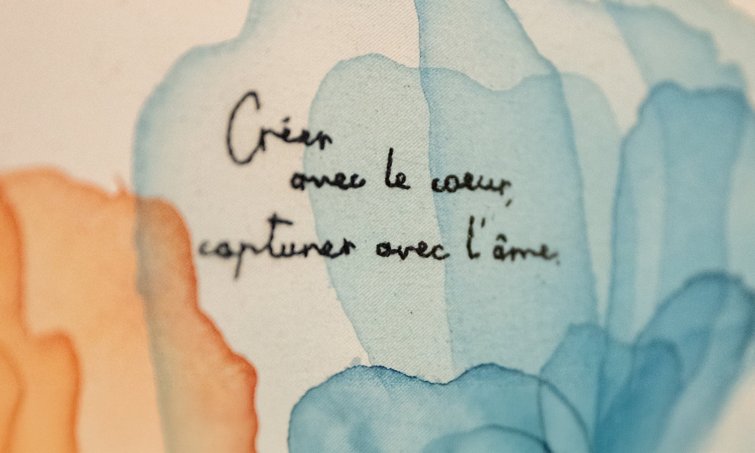 Une aquarelle aux fleurs bleues et orangées, avec l’inscription « Créer avec le cœur, capturer avec l’âme »