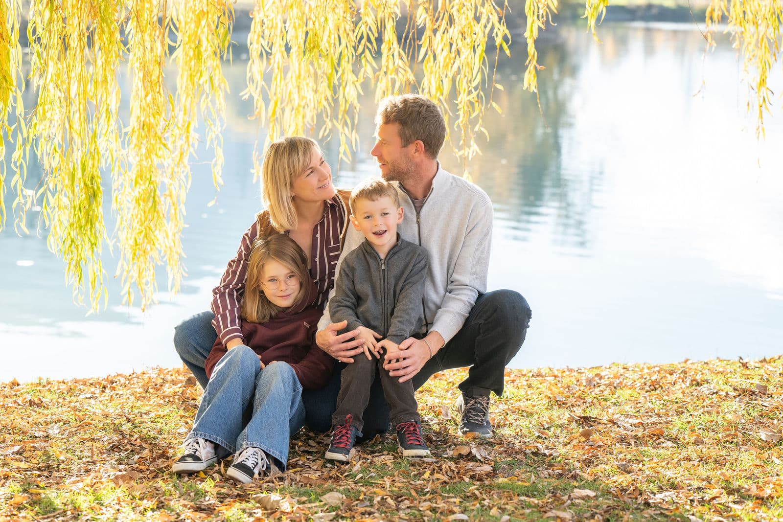 Une famille assise sous un saule, au bord de l’eau