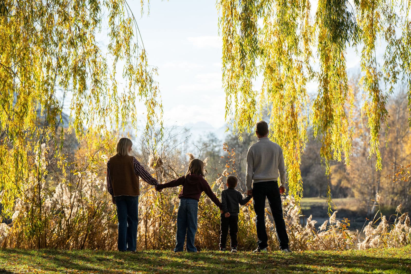 Une famille de dos, main dans la main, face au lac