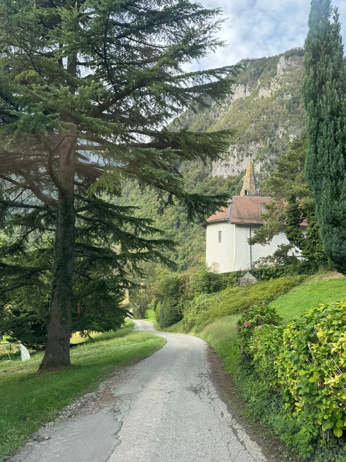 Une petite église blanche au bout d’un chemin, entre les arbres et la falaise