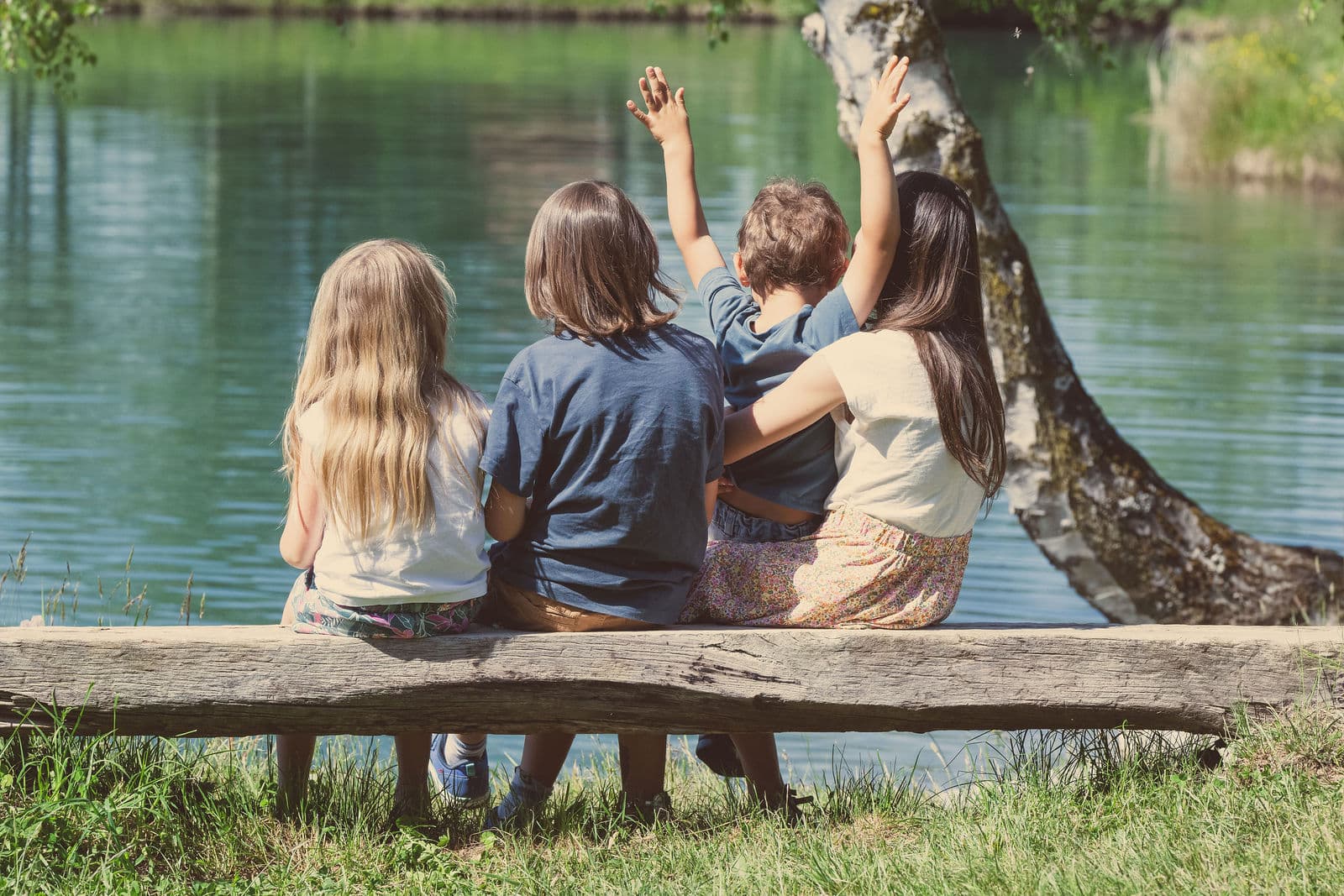 Une famille assise sur un banc de bois, face à l’étang