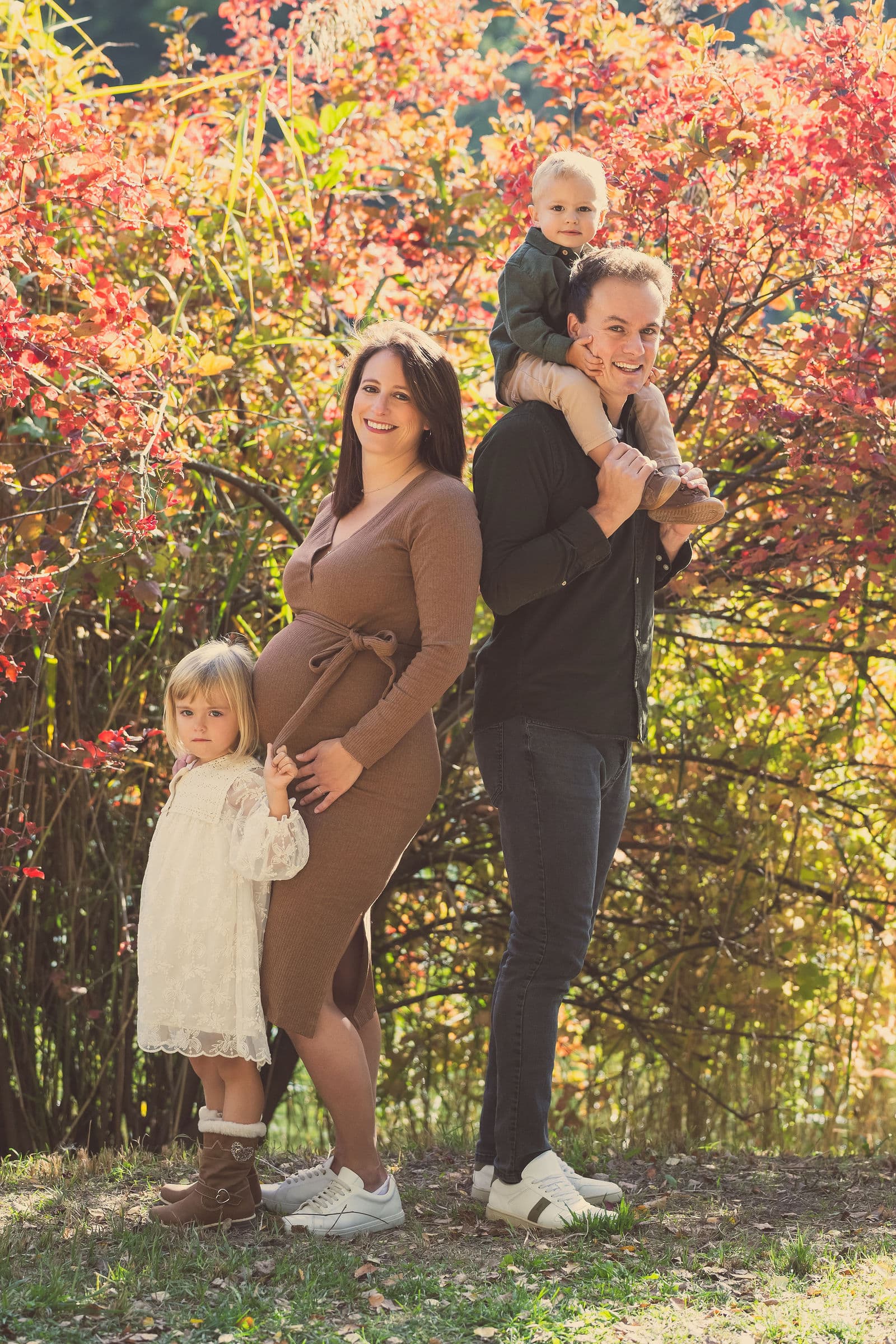 Une famille devant des feuillages d’automne rouges