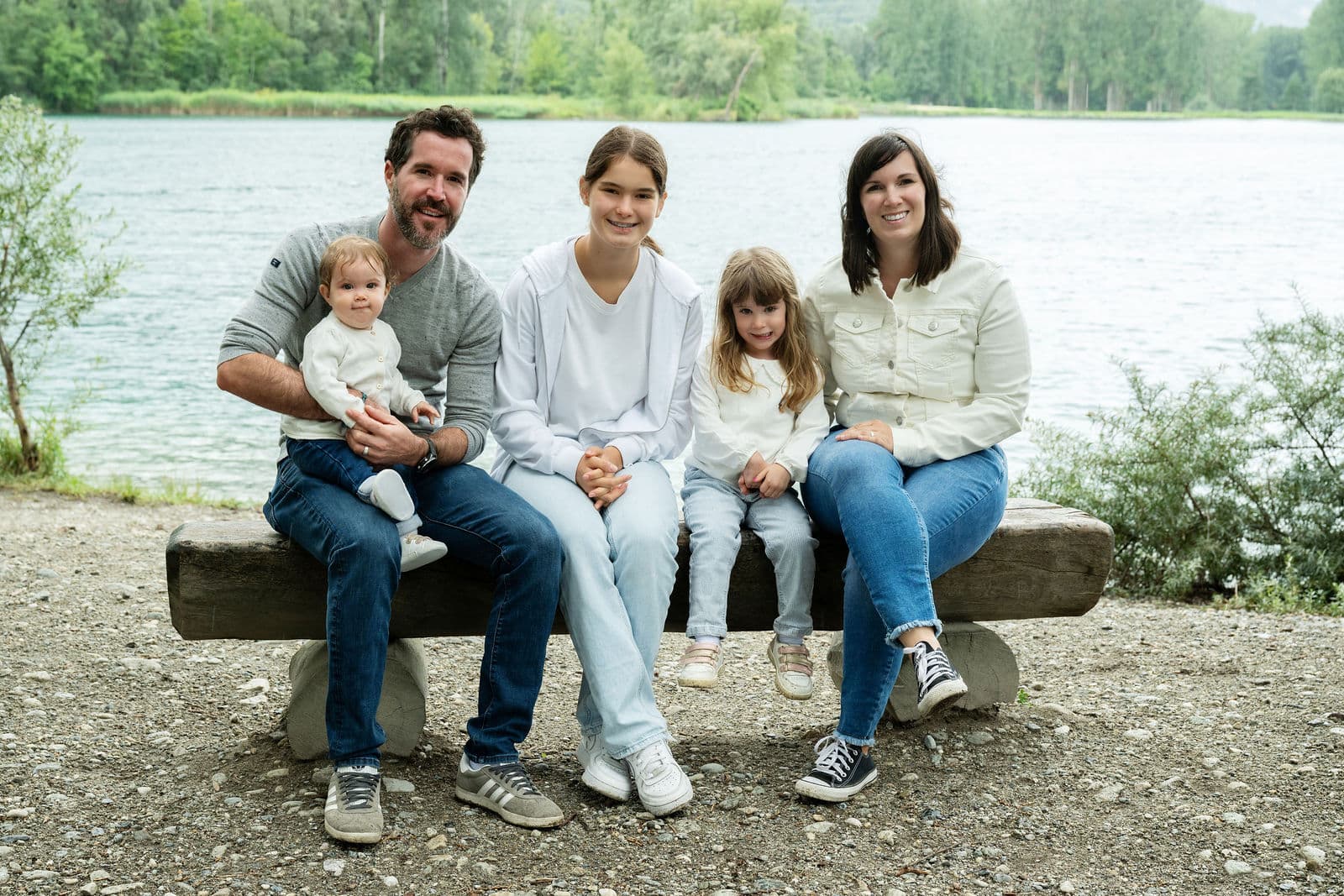 Une famille sur un banc de bois au bord de l’étang