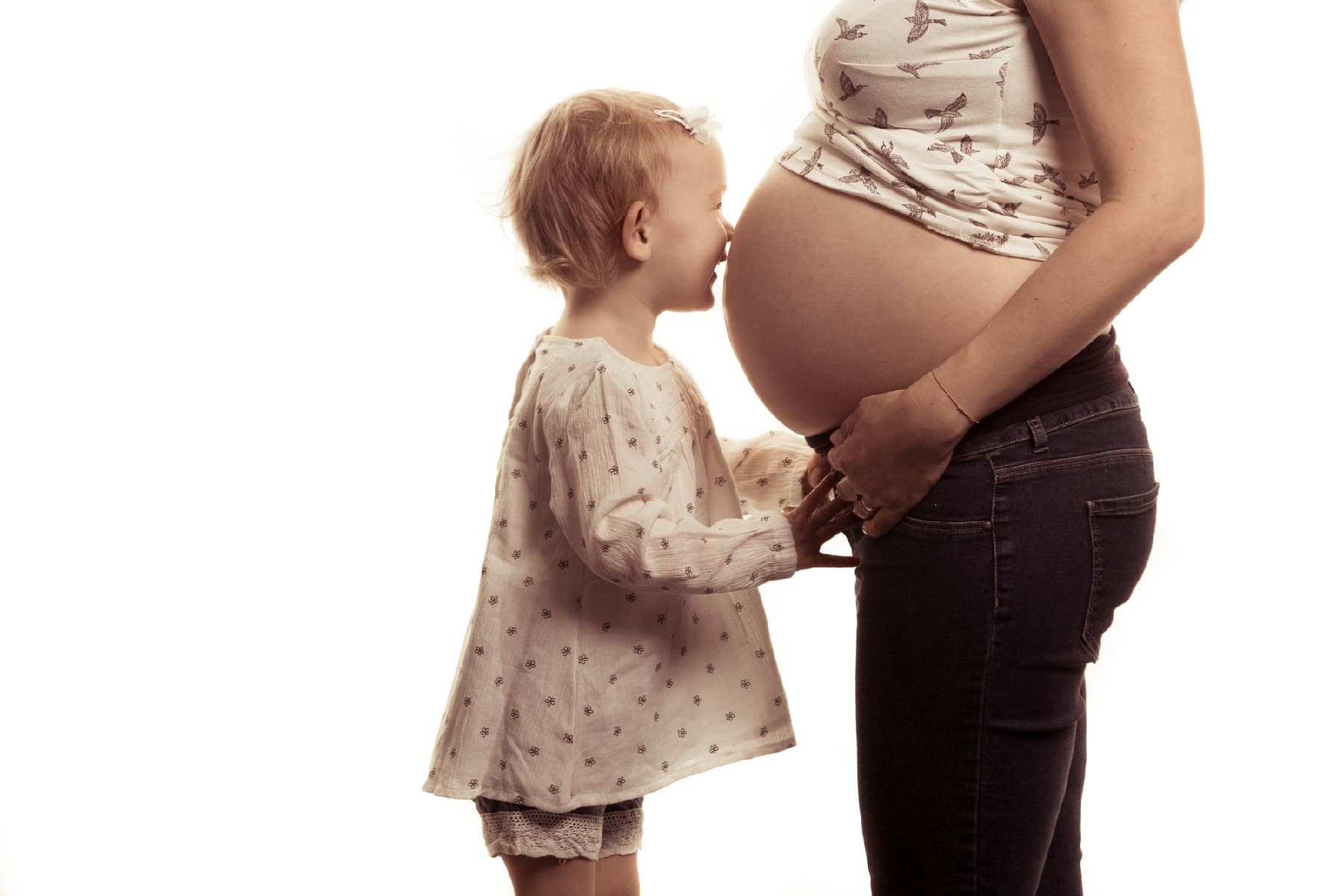 Une petite fille embrasse le ventre rond de sa maman