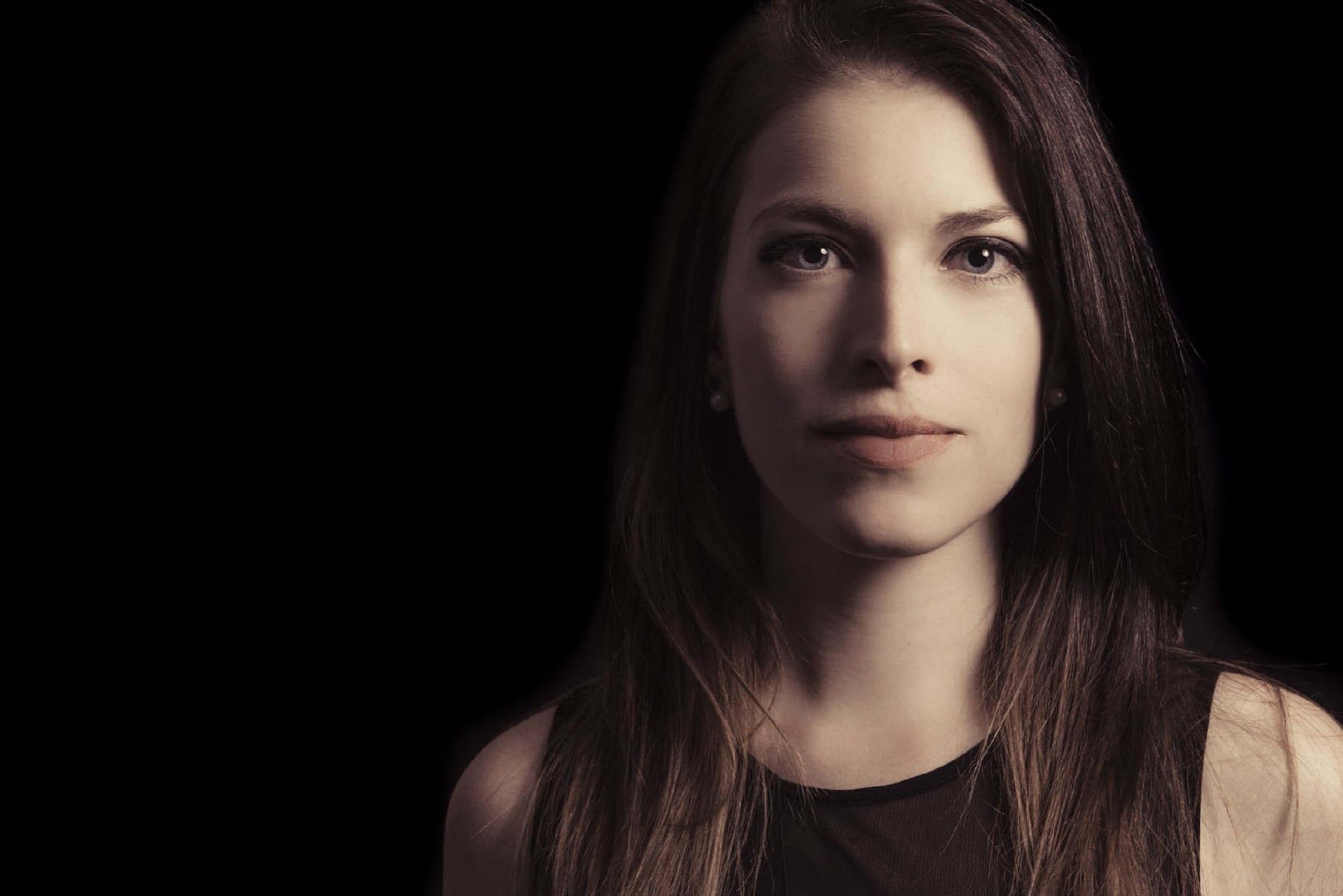 Portrait d’une jeune femme au regard direct, fond noir