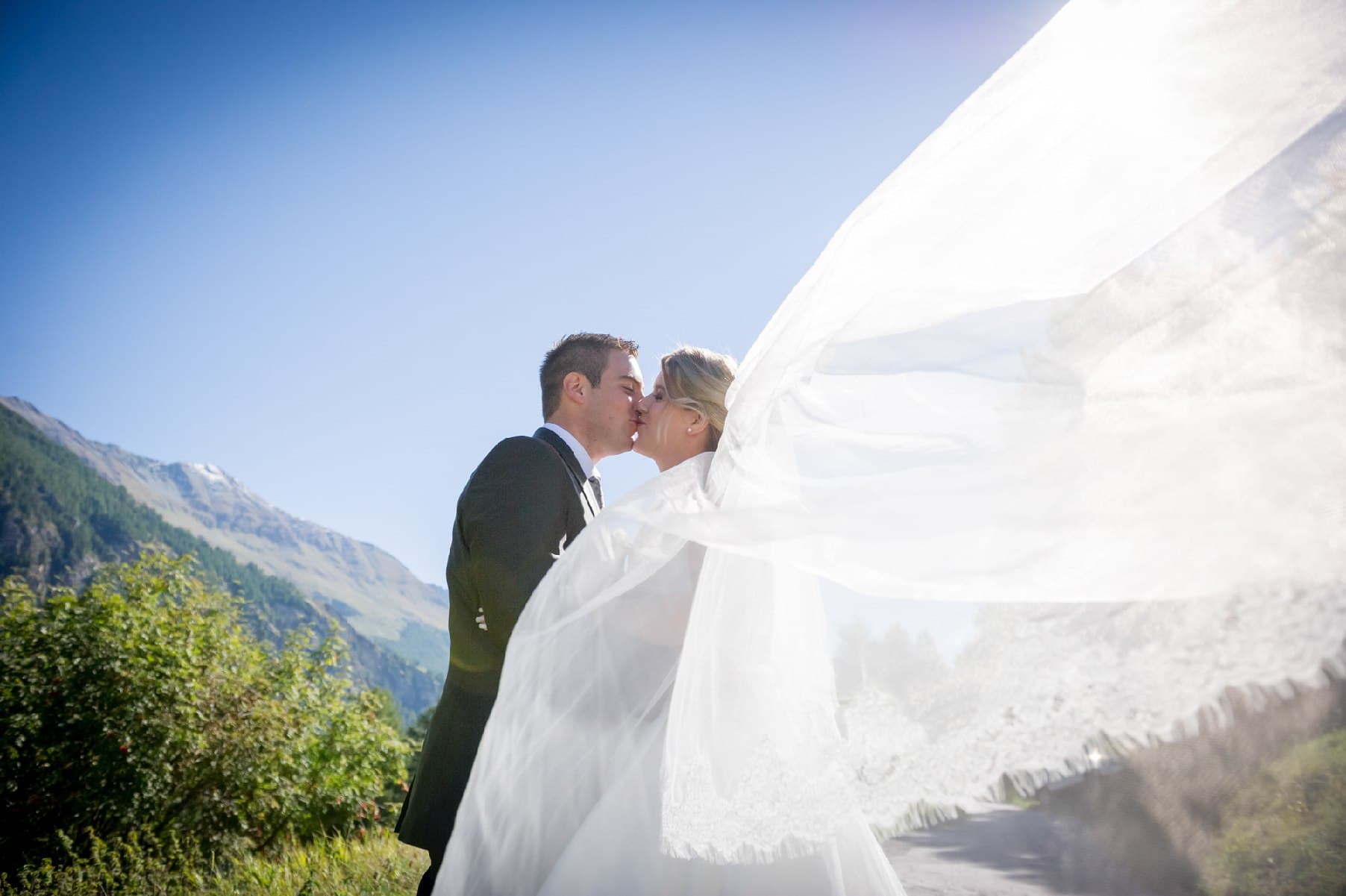 Baiser des mariés en montagne, le voile soulevé par le vent
