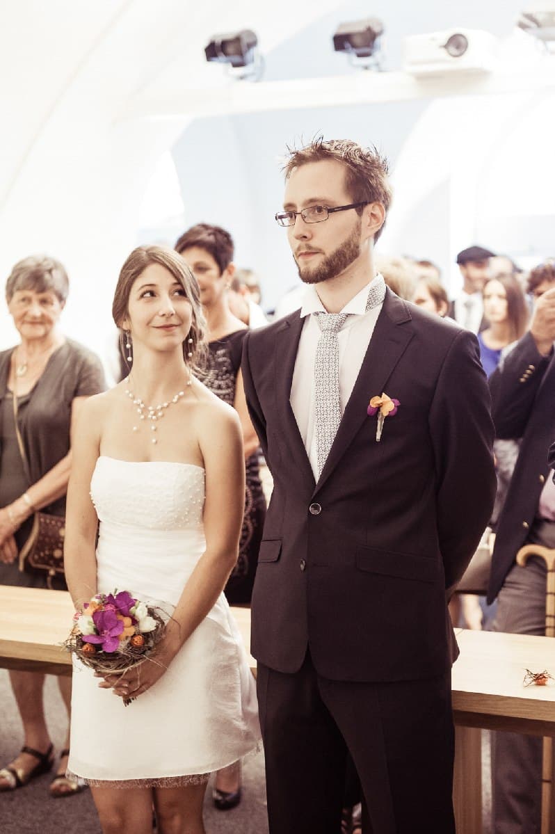 Cérémonie civile : la mariée sourit au marié, debout devant leurs invités