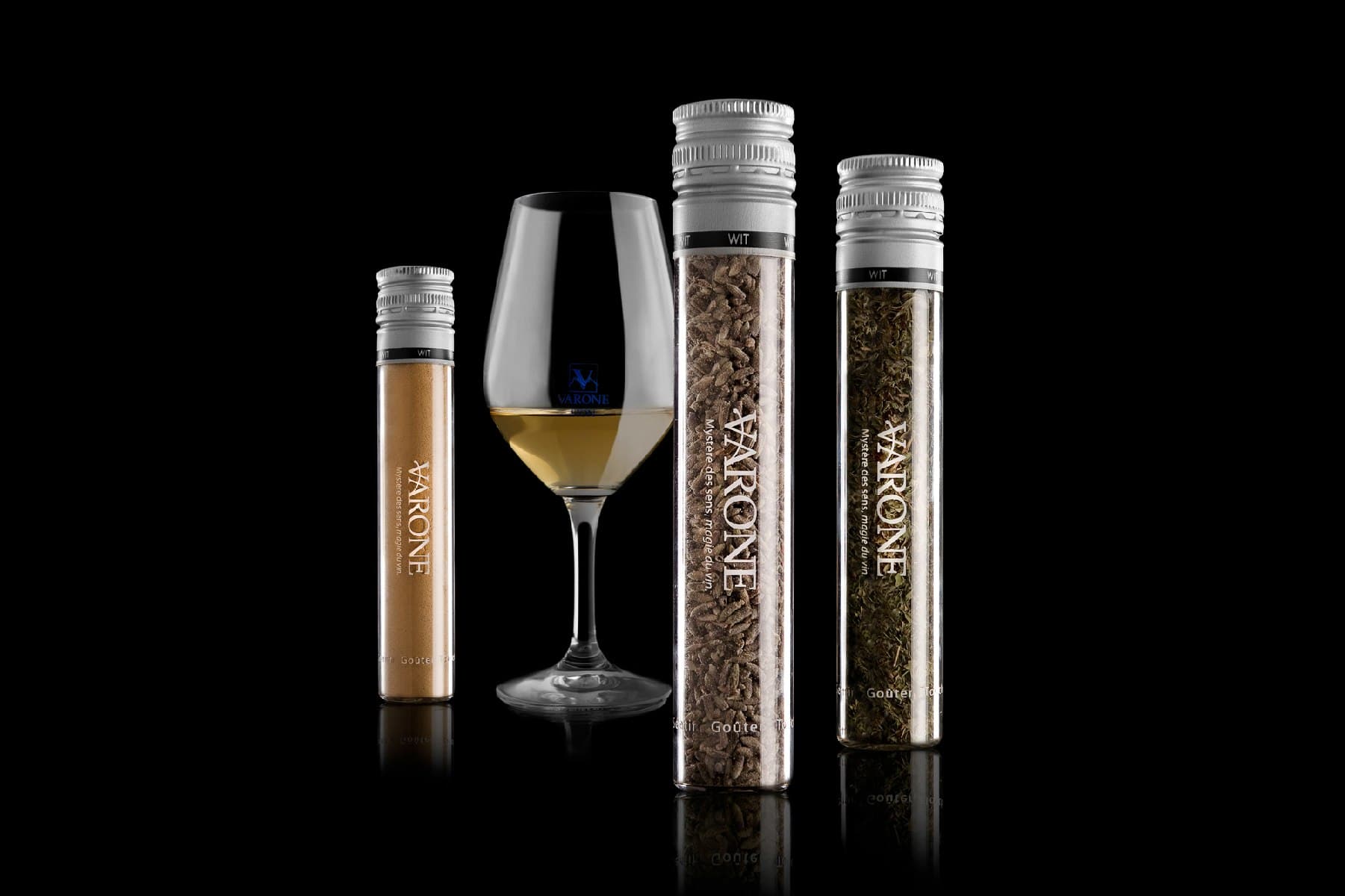 Trois tubes de dégustation de vin et un verre de vin blanc sur fond noir