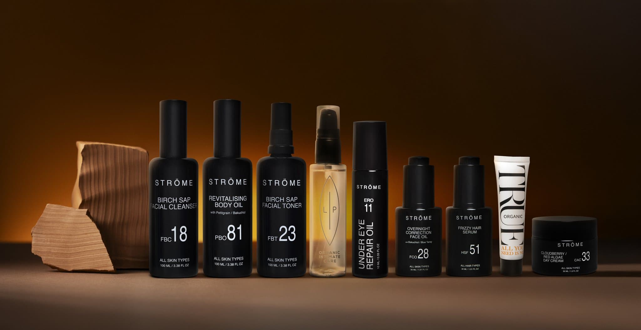 Gamme de flacons de soins noirs Ströme alignés sur un fond brun