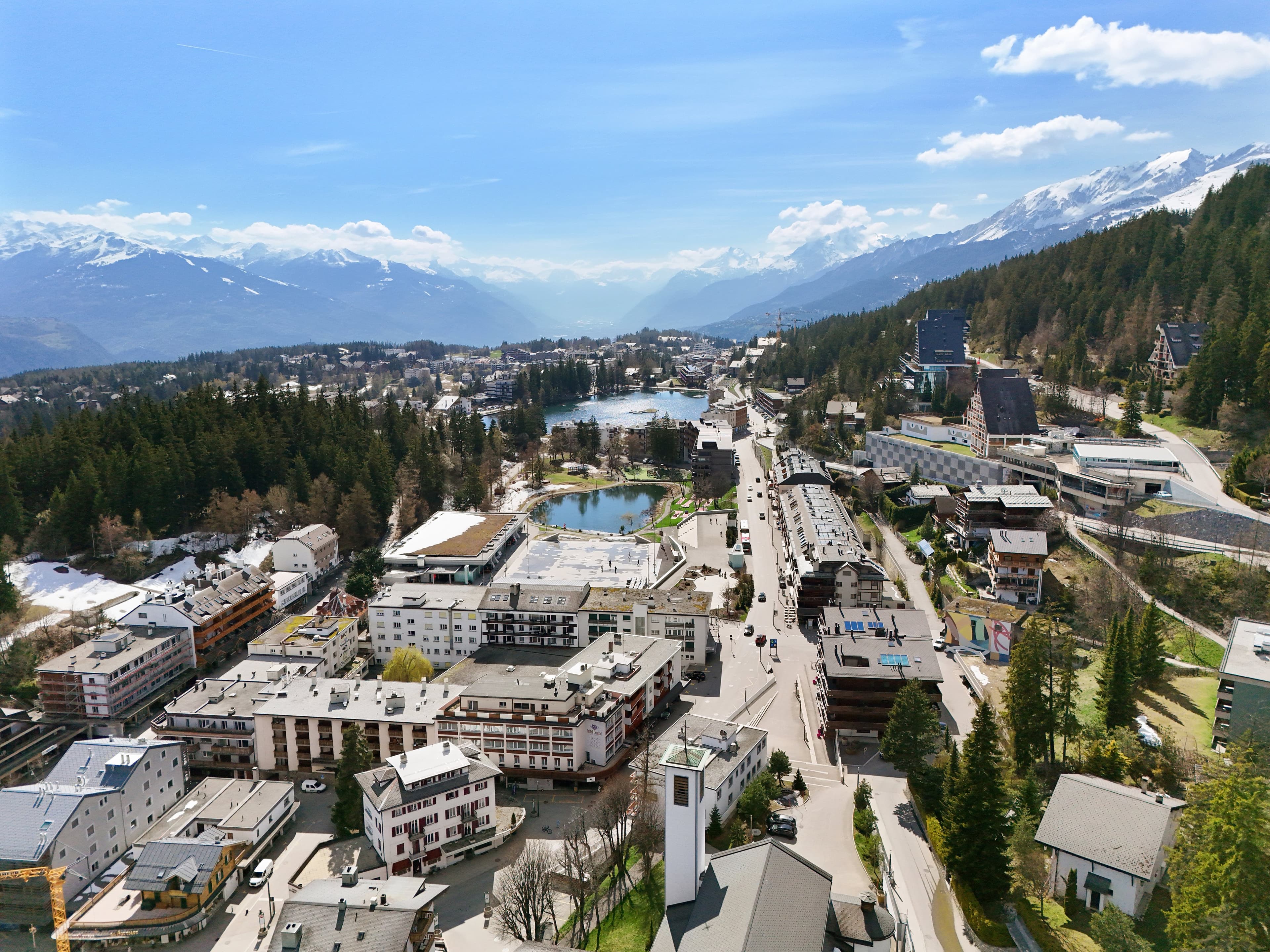 Vue aérienne de la station de Crans-Montana, ses rues et ses lacs, la vallée du Rhône au loin