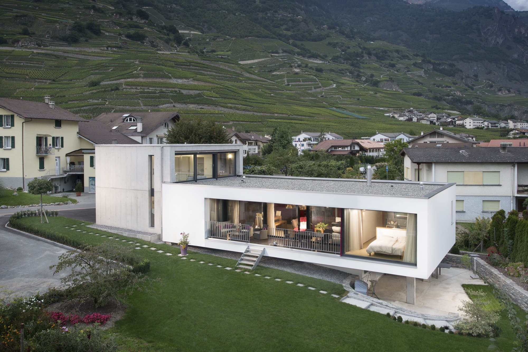 Maison contemporaine blanche au rez vitré et éclairé, vignoble en terrasses à l’arrière