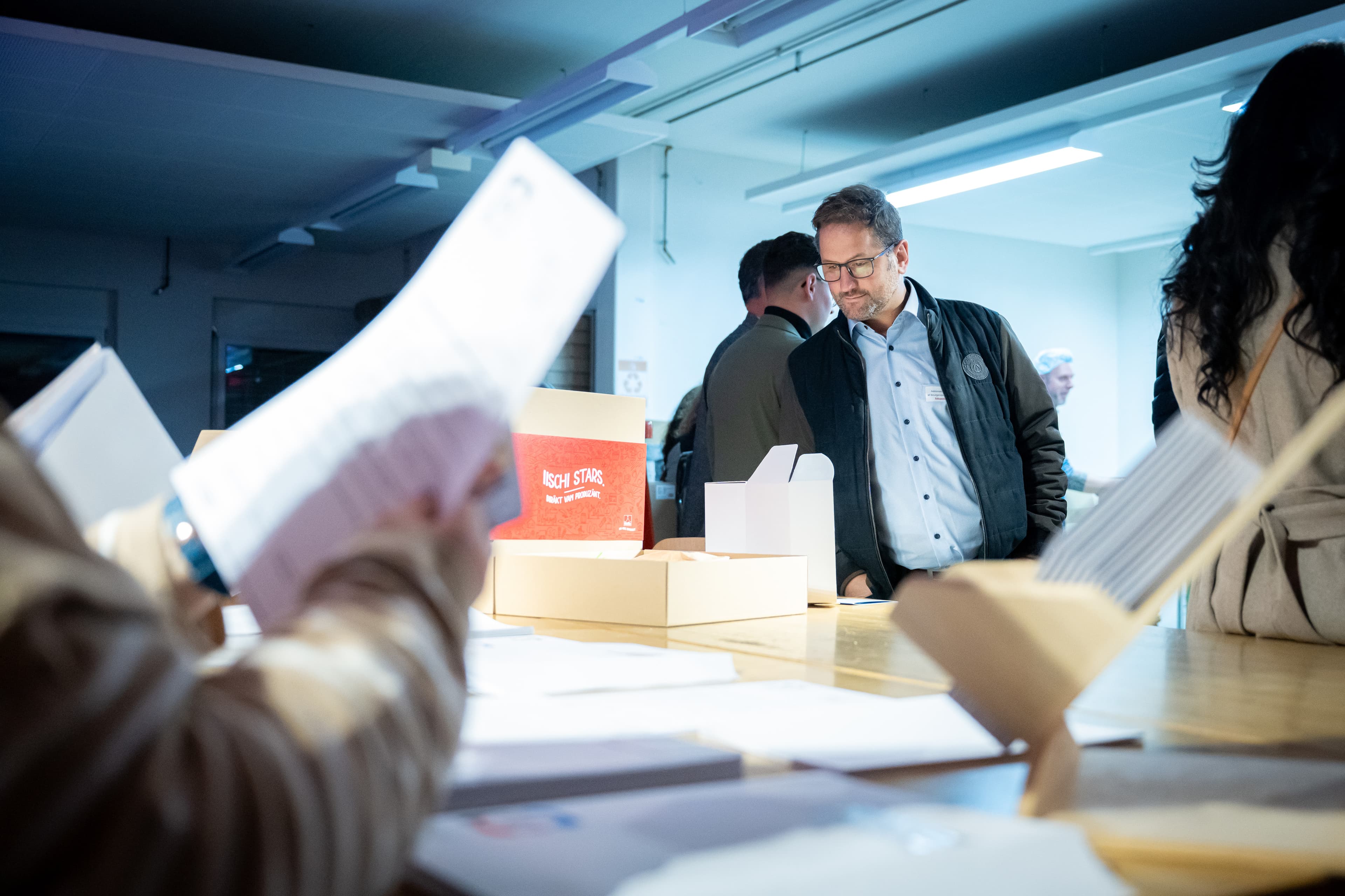 Invités penchés sur des documents et des coffrets posés sur une longue table, lors de la Nuit de l’Excellence de Valais Excellence