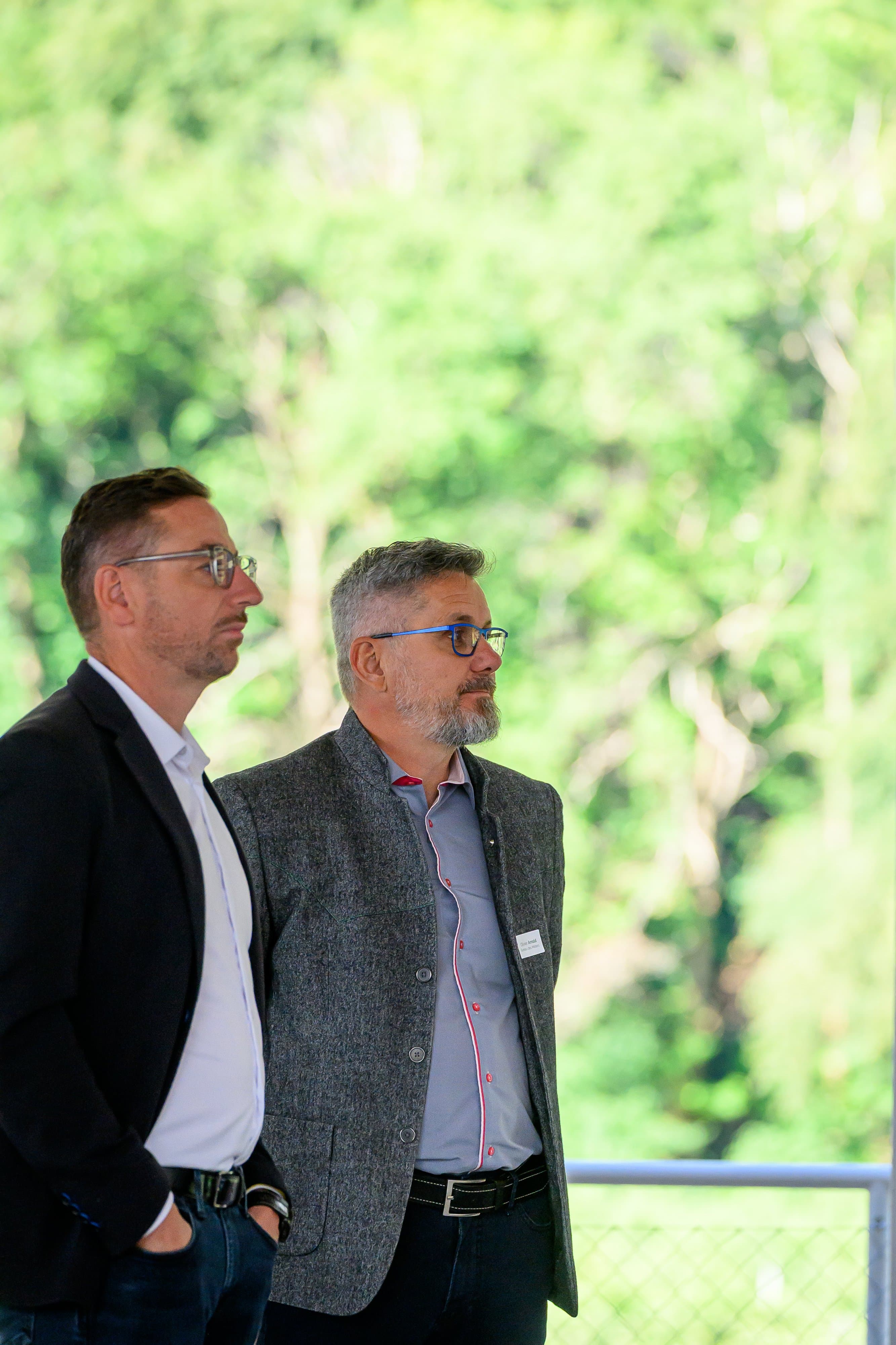 Deux membres qui écoutent côte à côte, debout devant un rideau de verdure